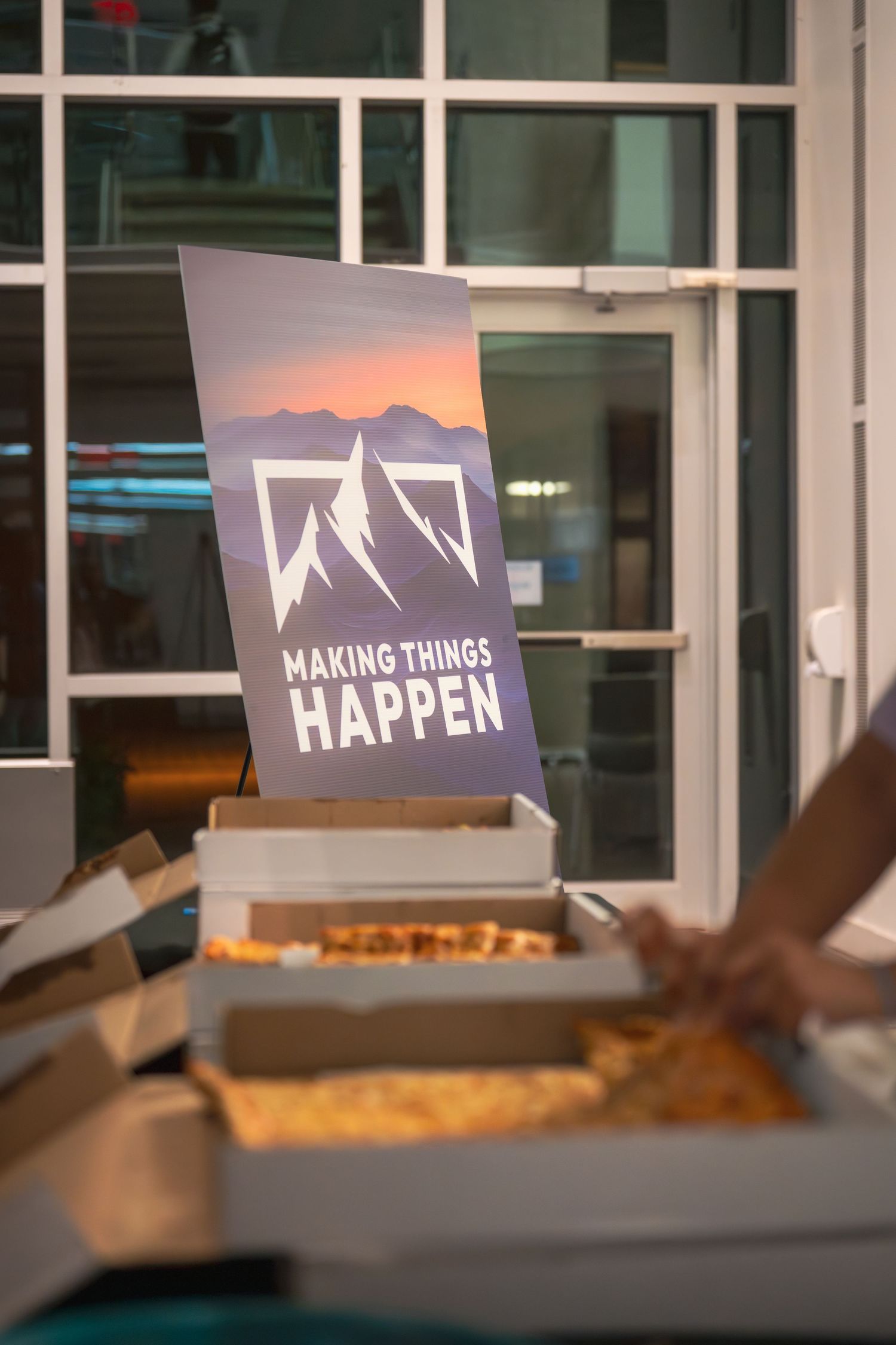 Multiple 'Making Things Happen' signs displayed near glass windows with food boxes in foreground.