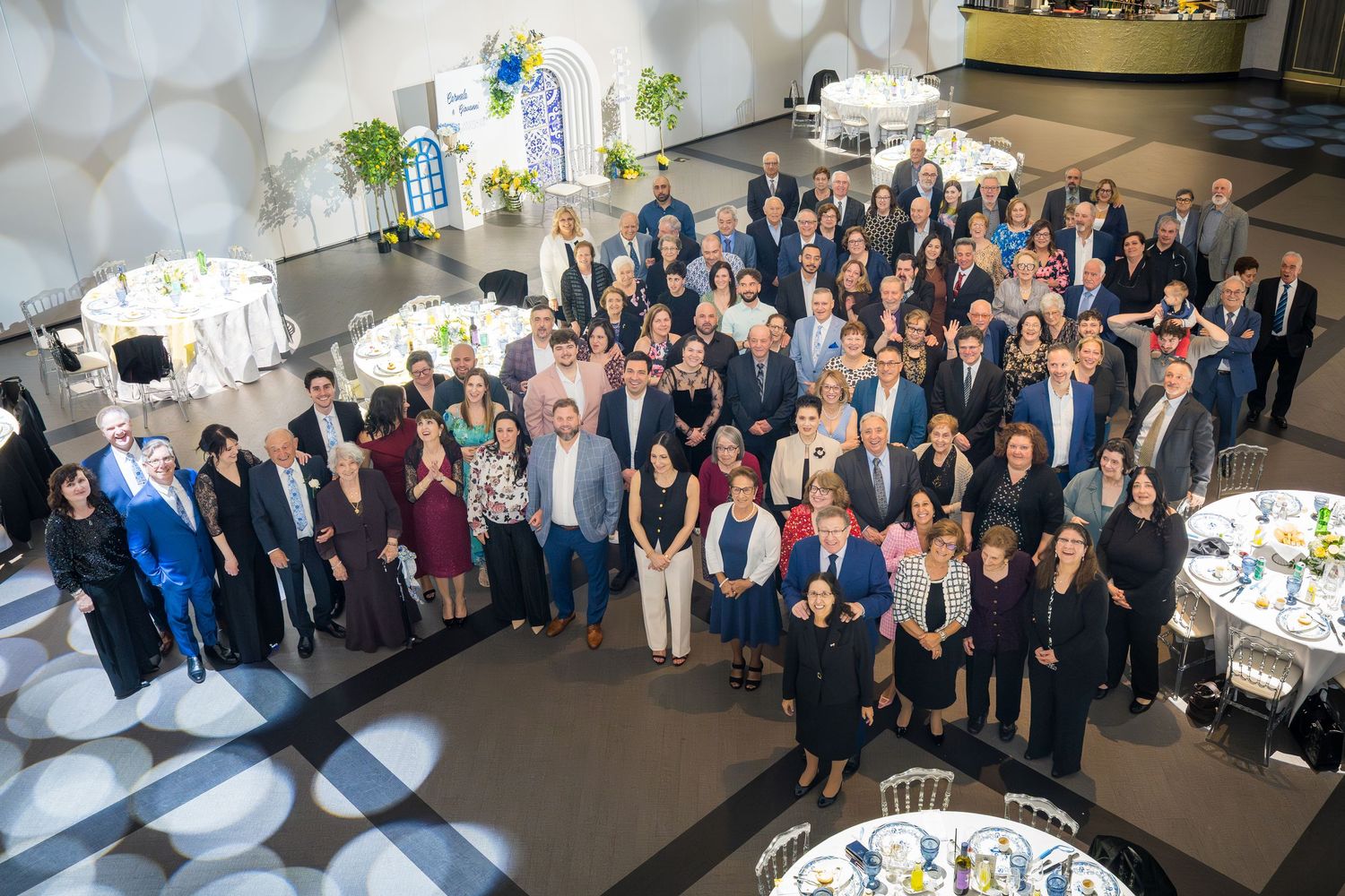 Aerial view of large wedding reception group photo with blue and yellow decorated venue.
