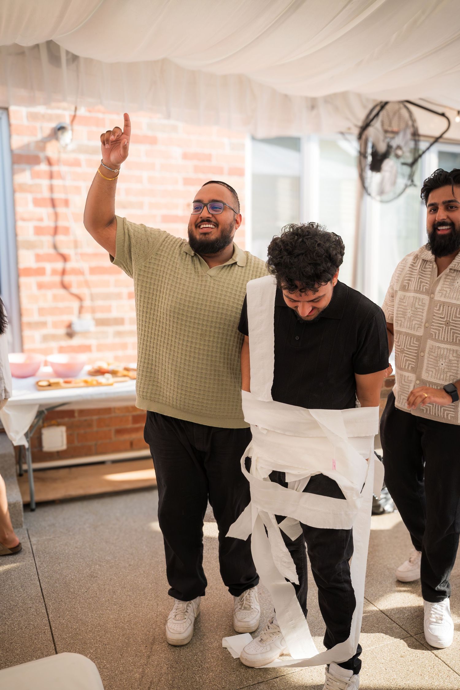 A group of guests laughing and having fun at an indoor event with white drapes.