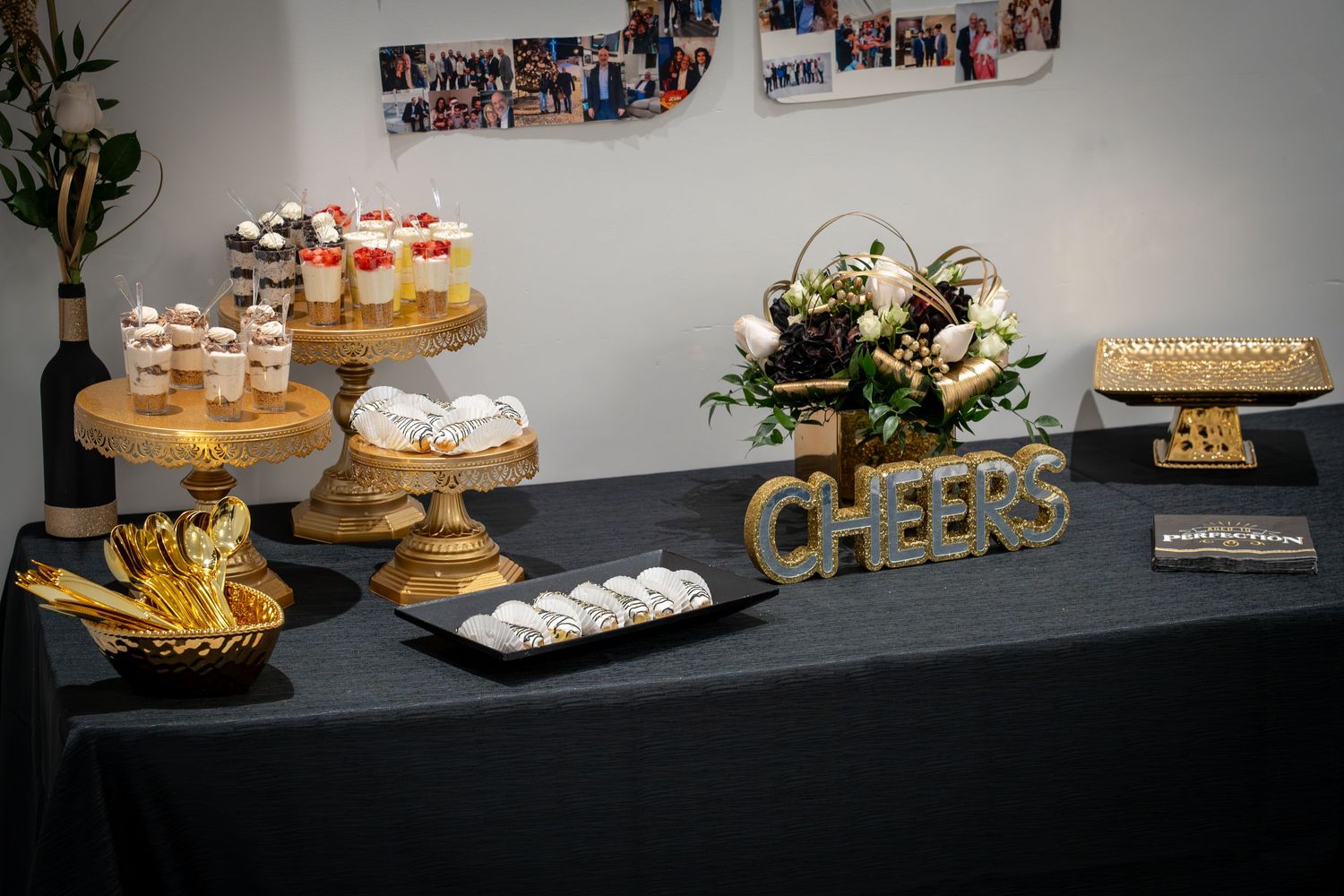 Dessert table with cupcakes and treats arranged on black tablecloth.