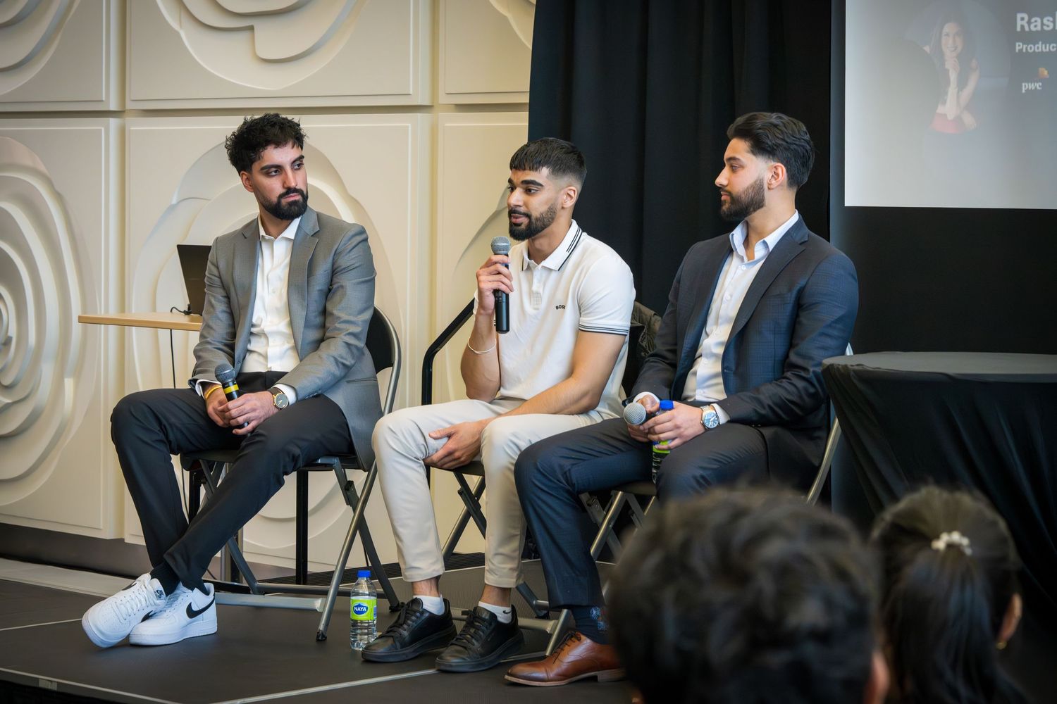 Panel members seated on stage having animated discussion during professional event.