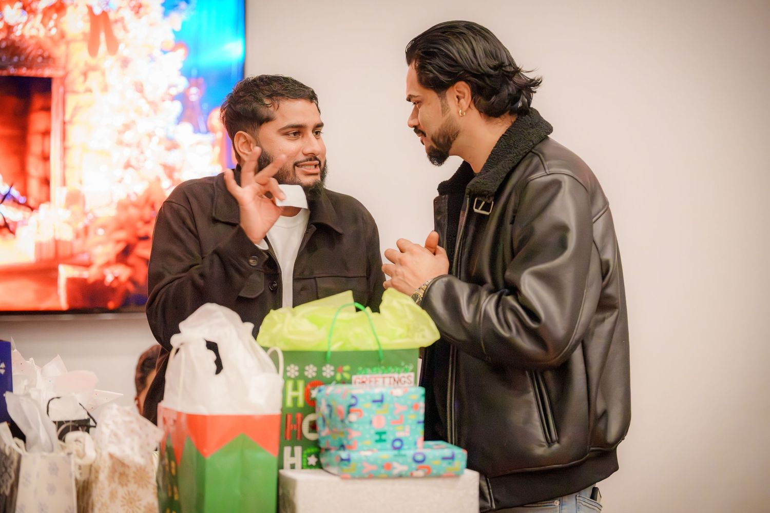People engaged in conversation at an indoor gathering with decorative lighting in the background.