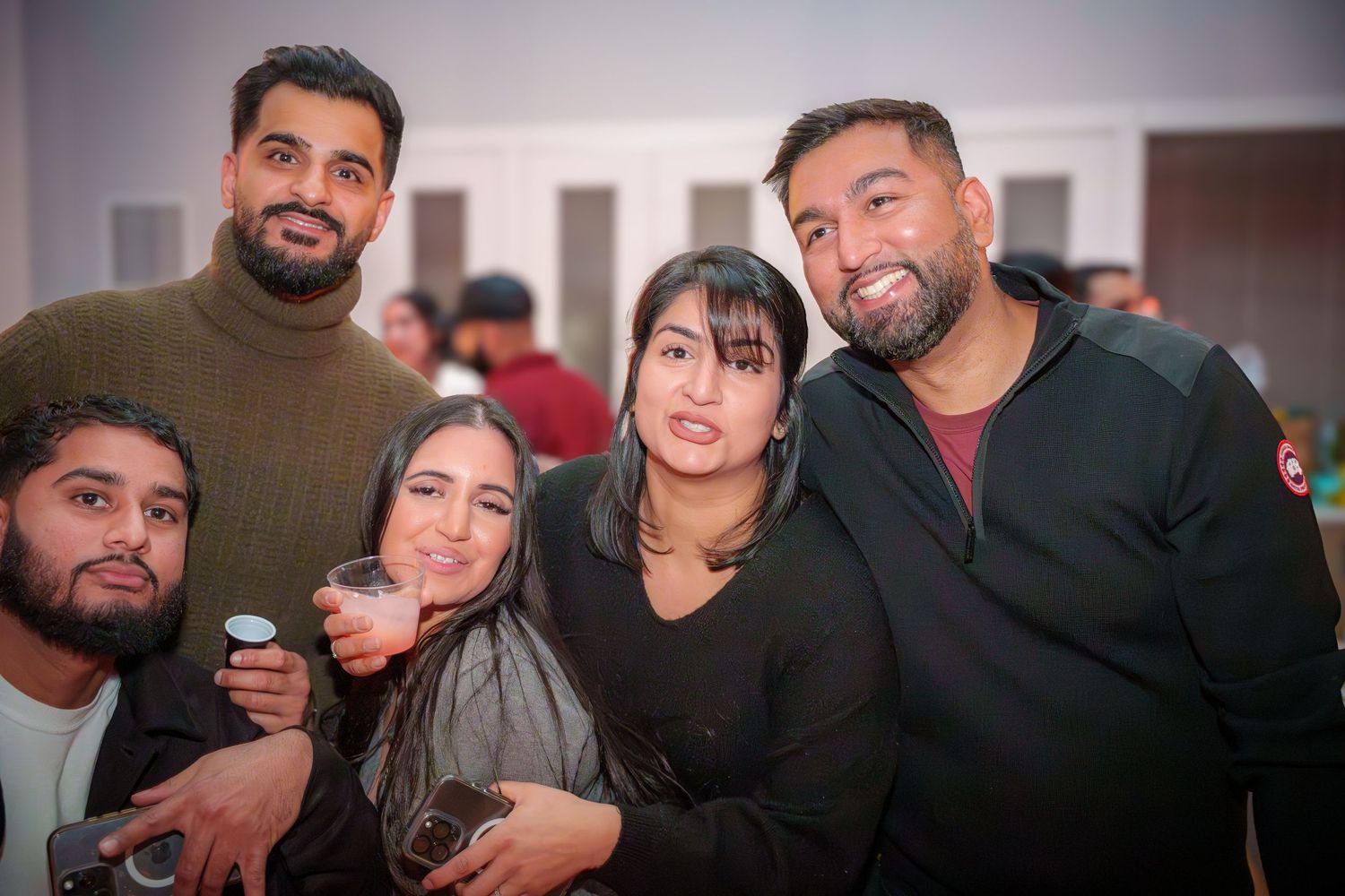 Friends gathered together for a group photo at an indoor social event.