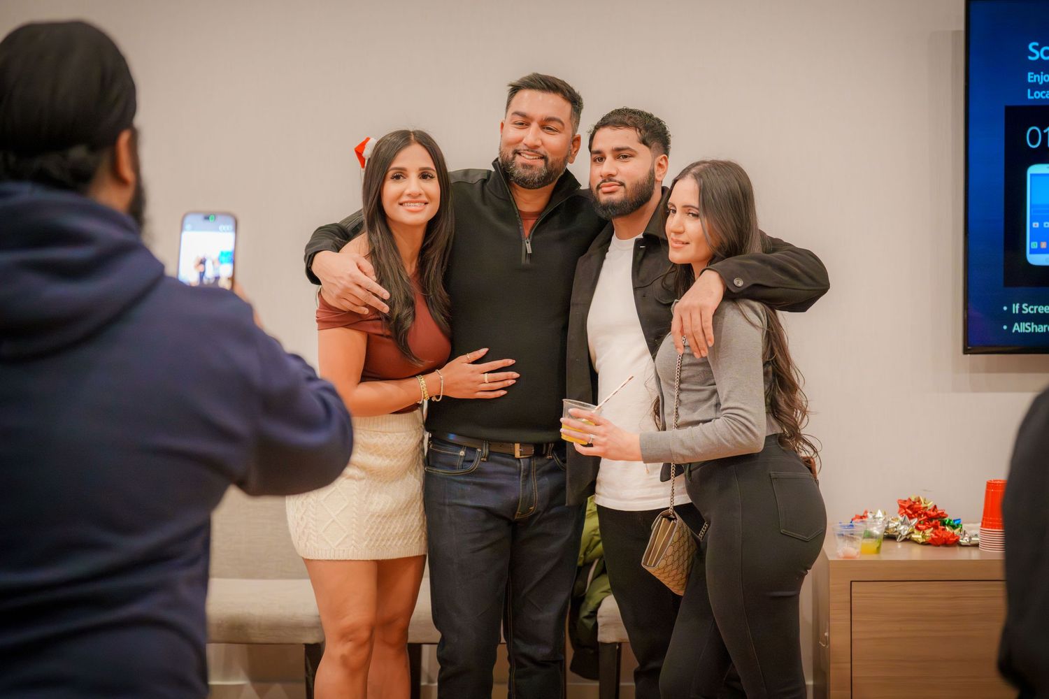 Group photo at an indoor party with warm lighting and casual atmosphere.