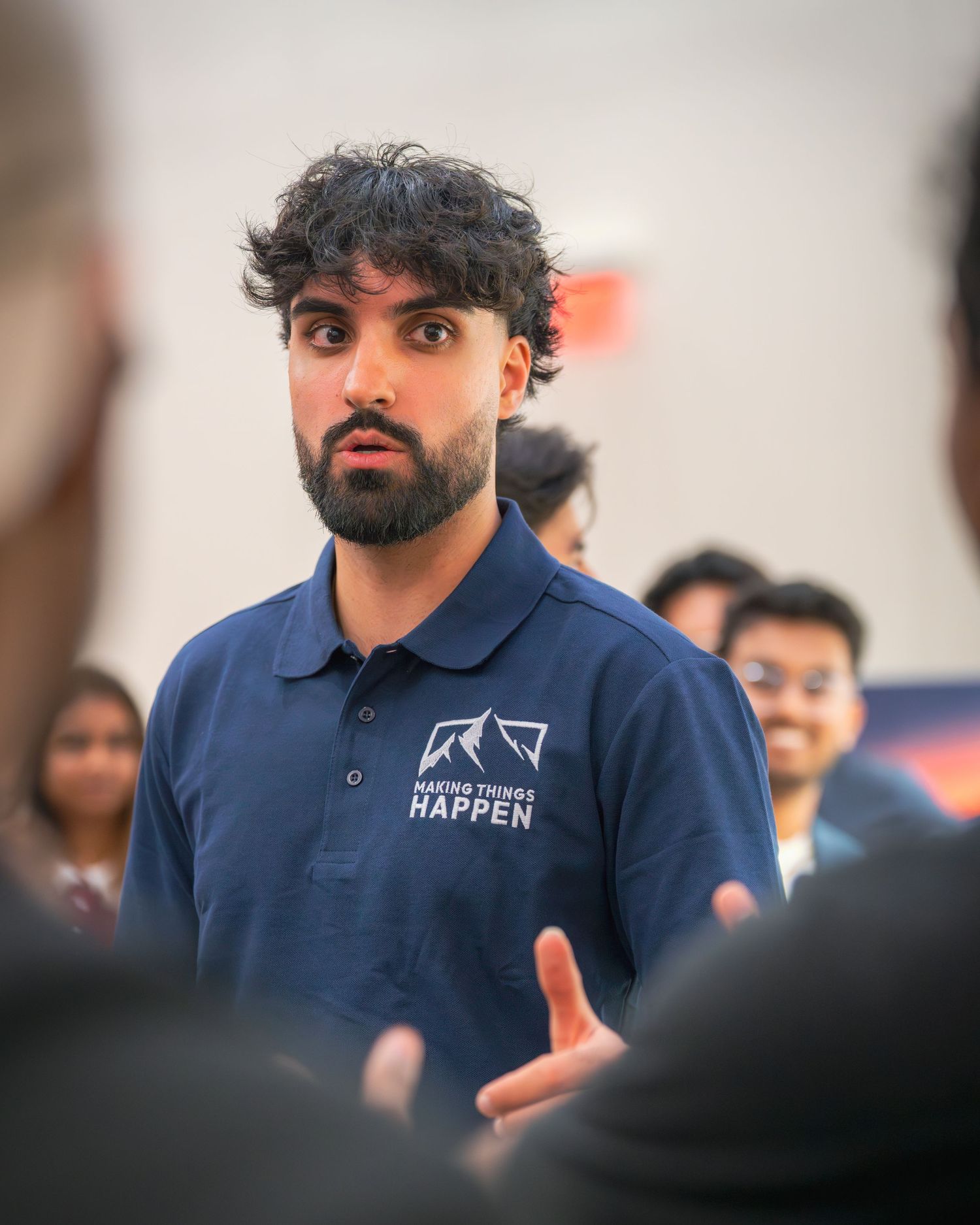 Presenter in branded polo shirt speaks expressively during a business presentation.