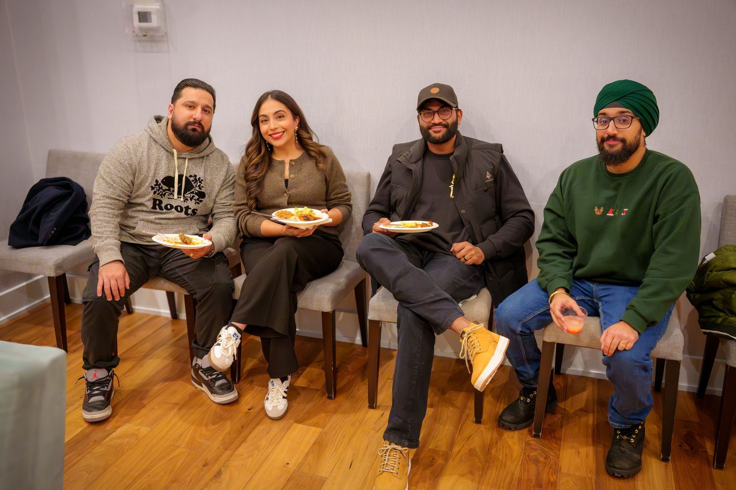 Group sitting together on benches at an indoor social gathering.