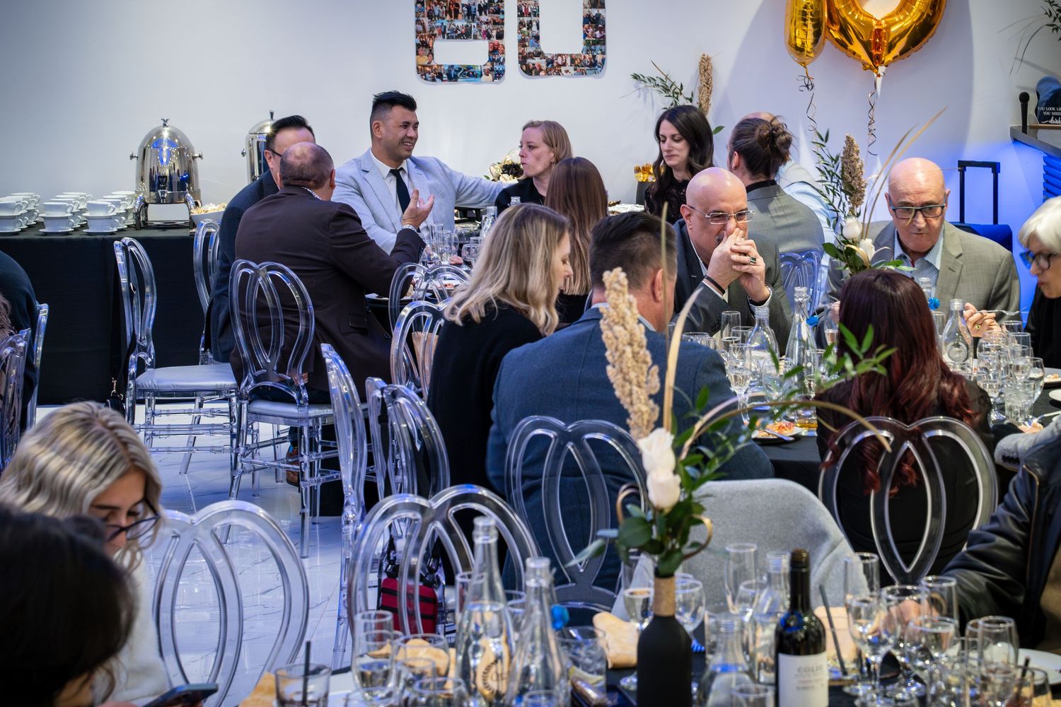 Corporate celebration with gold balloon decorations and guests mingling at tables.