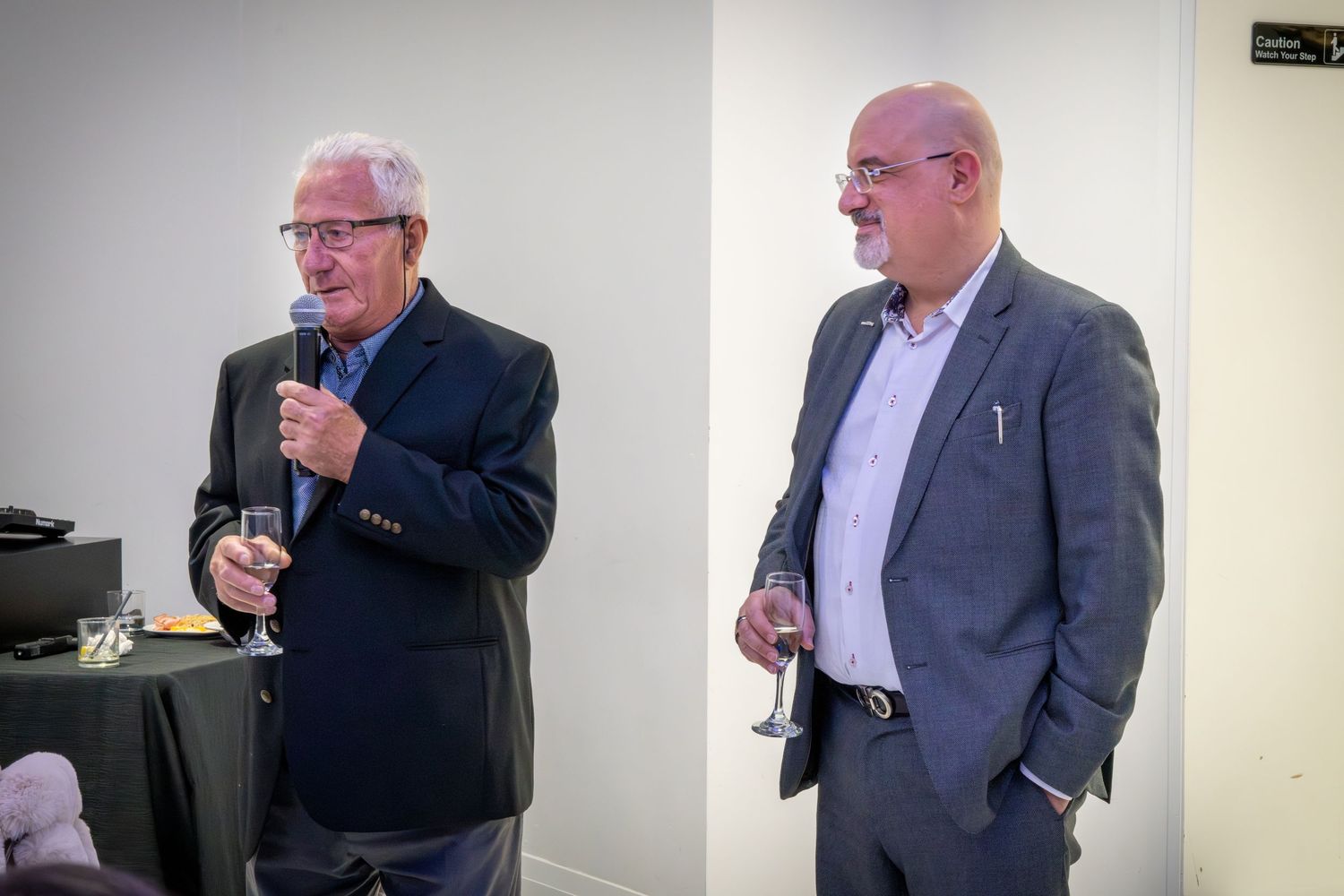 Two gentlemen in suits giving speeches at a formal celebration.