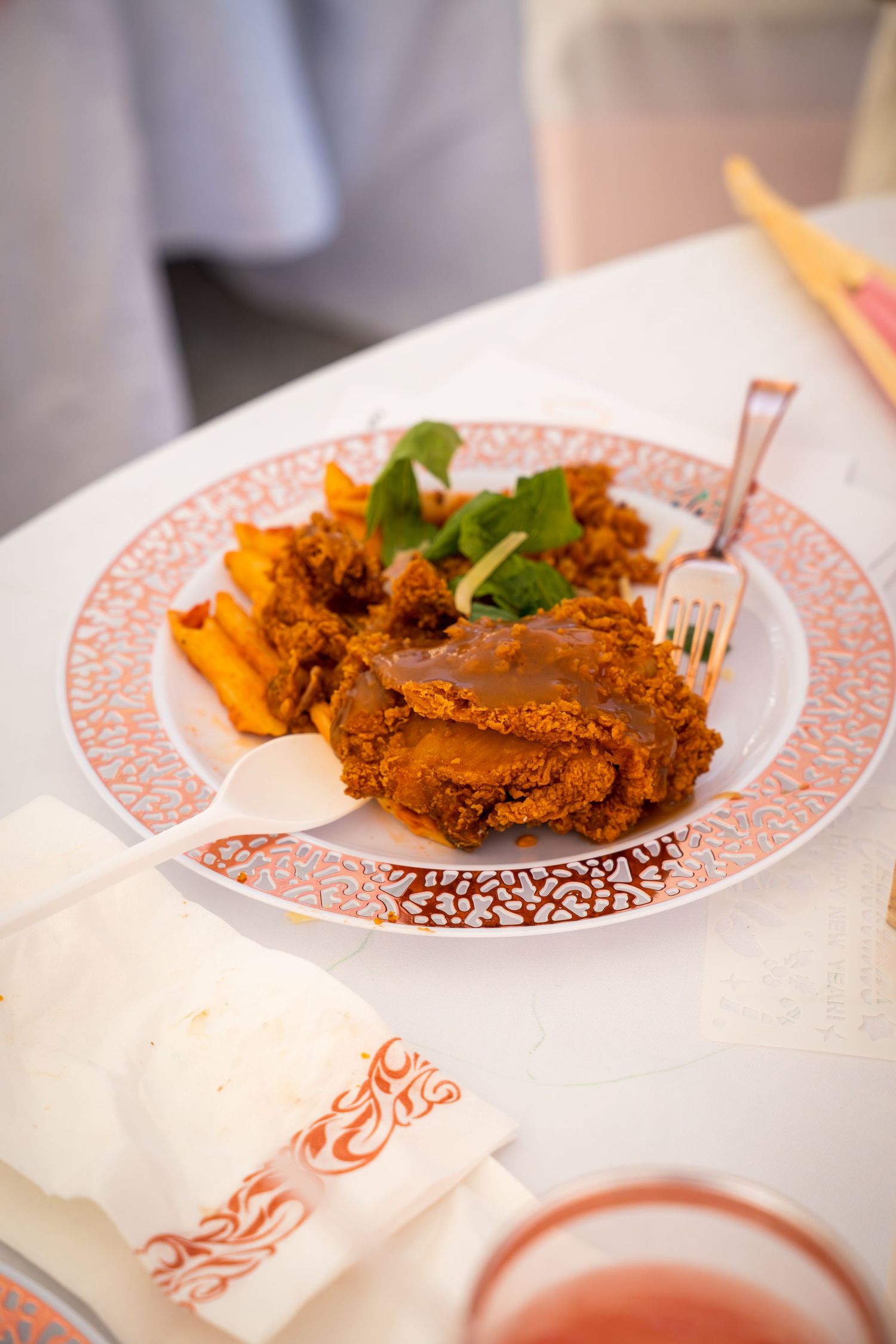 Crispy fried chicken with sides served on a decorative plate with pink trim.