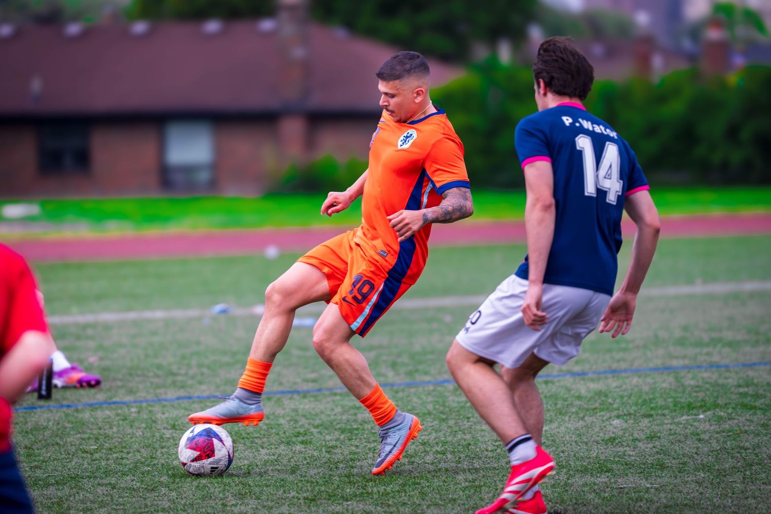 Players in orange and navy jerseys battle for control during a soccer match.