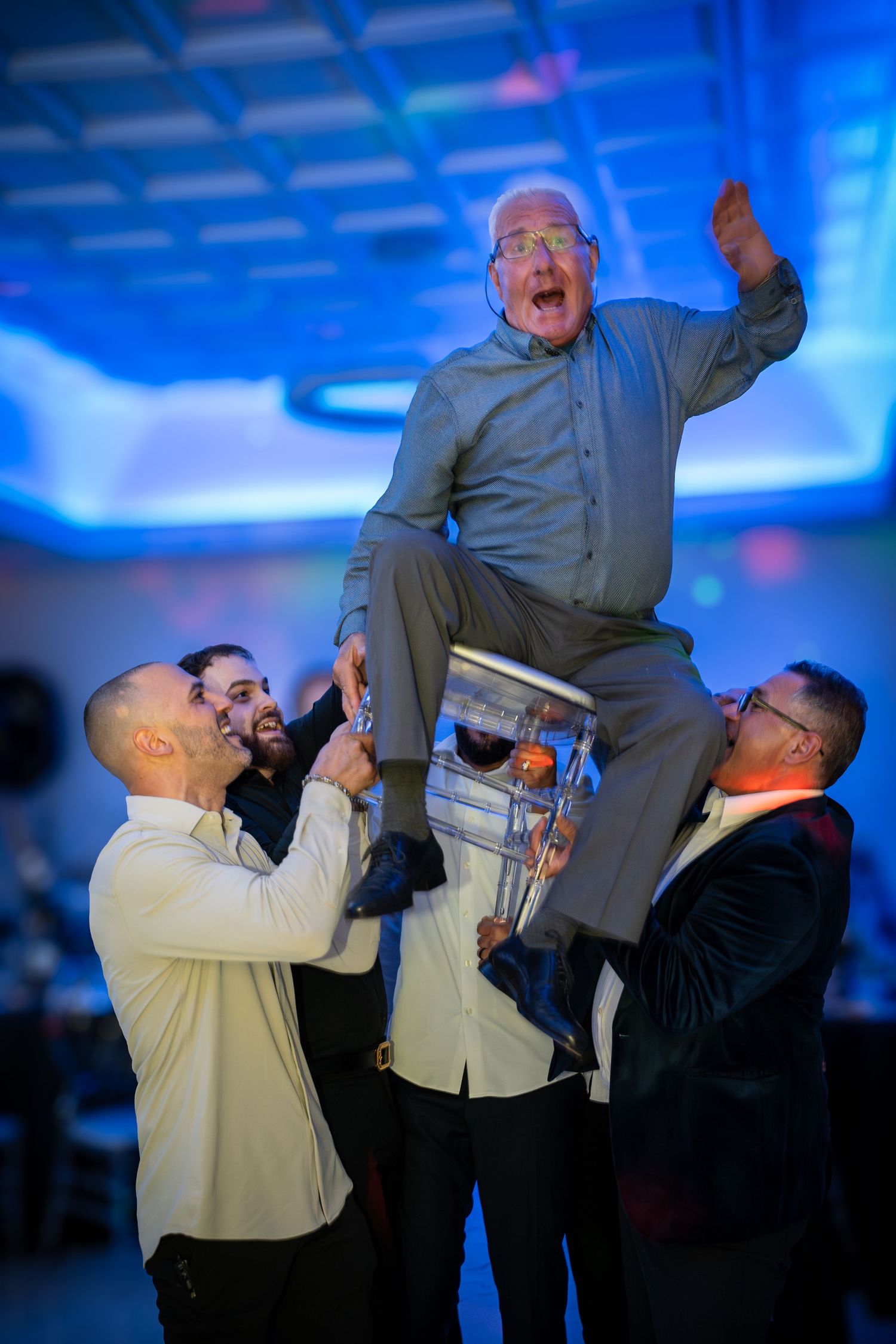 Sequence of playful group poses showing people lifting and jumping in blue lighting.