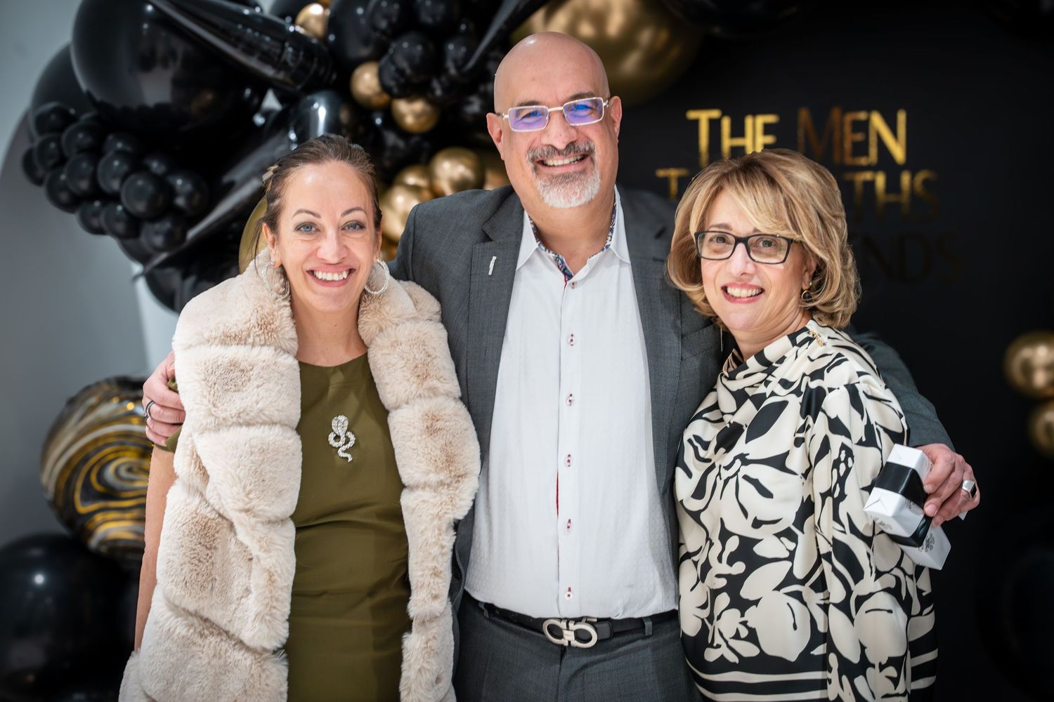 Formal group photos with gold balloons and black backdrop decorations.