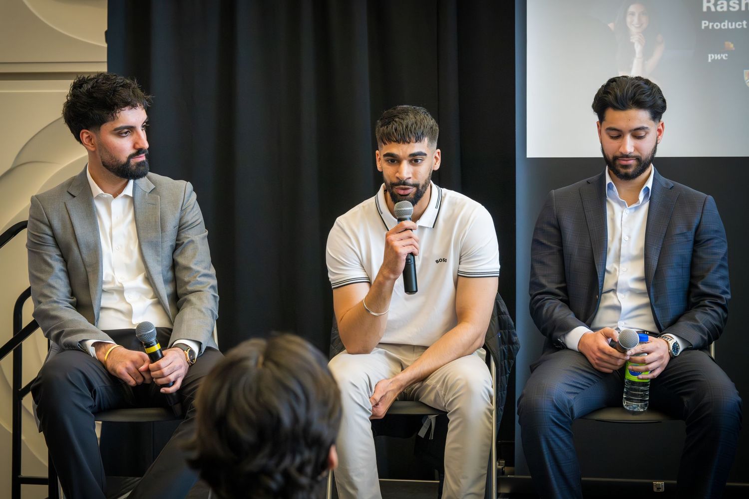 Group of speakers in business casual attire participating in panel discussion event.