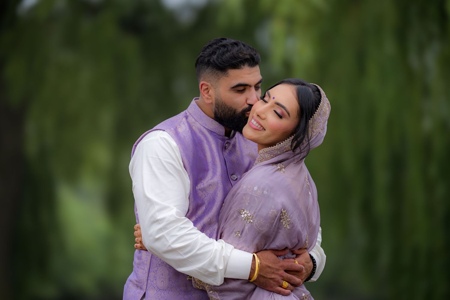 A romantic couple in traditional dress share a tender moment against a natural backdrop.
