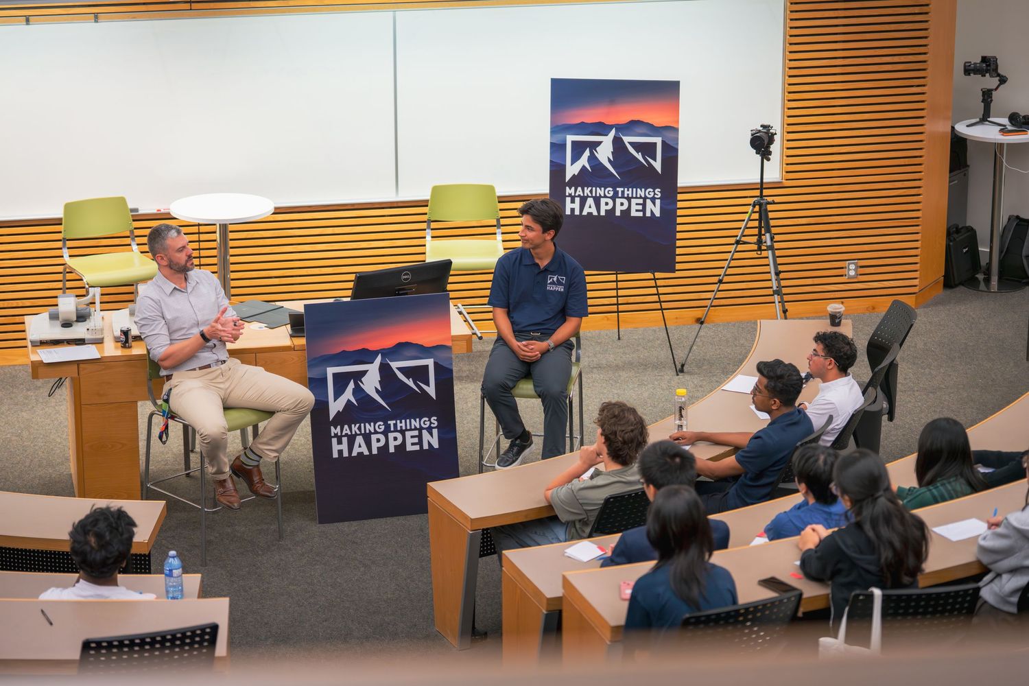 Panoramic view of a modern lecture hall with tiered seating and wood accent walls.