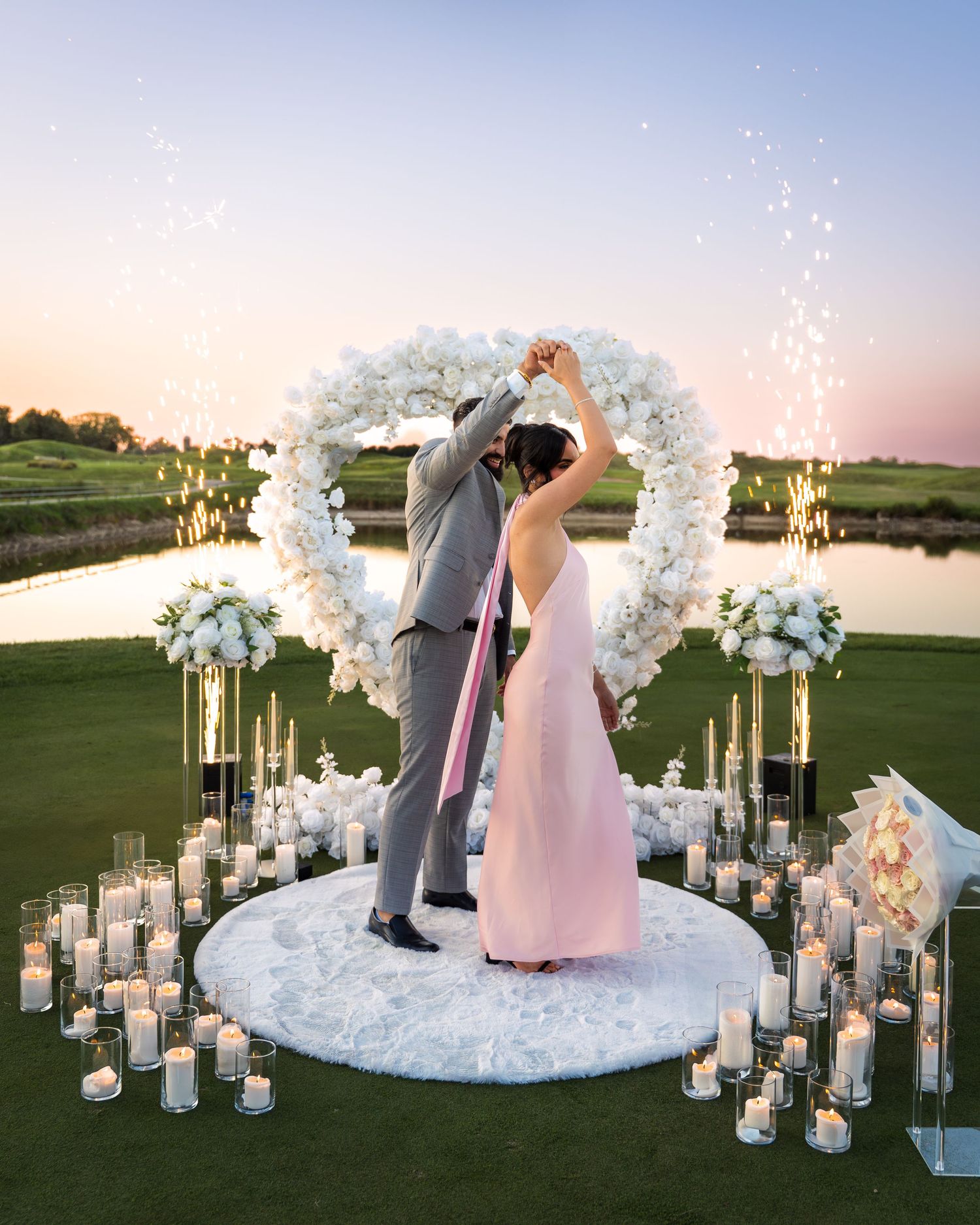Romantic wedding venue decoration with illuminated white floral arches at dusk.