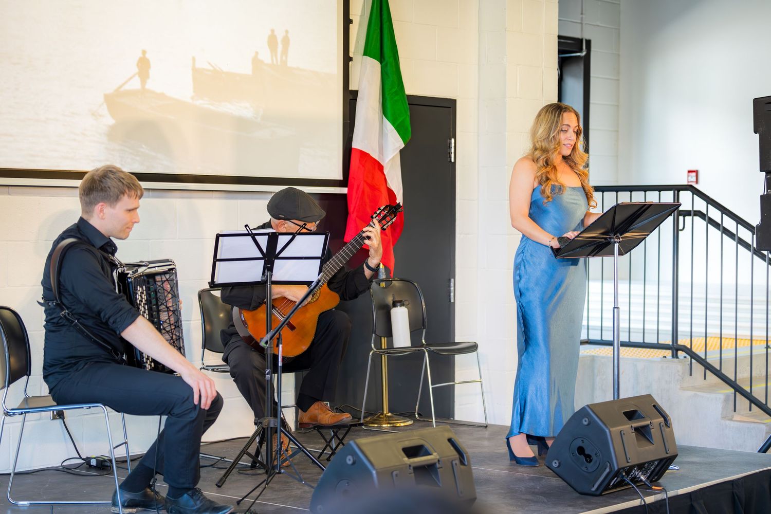 Live musical trio performing on stage with accordion, guitar, and female vocalist at a Neapolitan Ice Cream event.