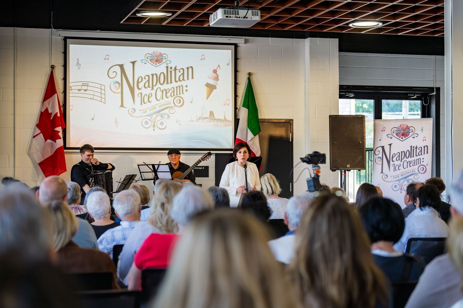 Neapolitan Ice Cream event presentation with live musicians and audience in a bright venue with Canadian and Italian flags.