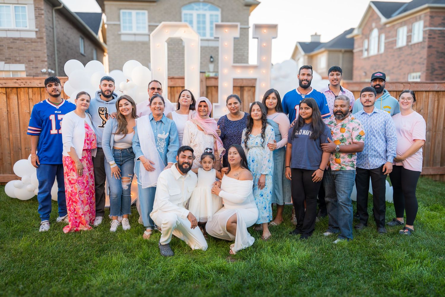 Large extended family group photo at outdoor gender reveal party with OH BABY balloon decorations.