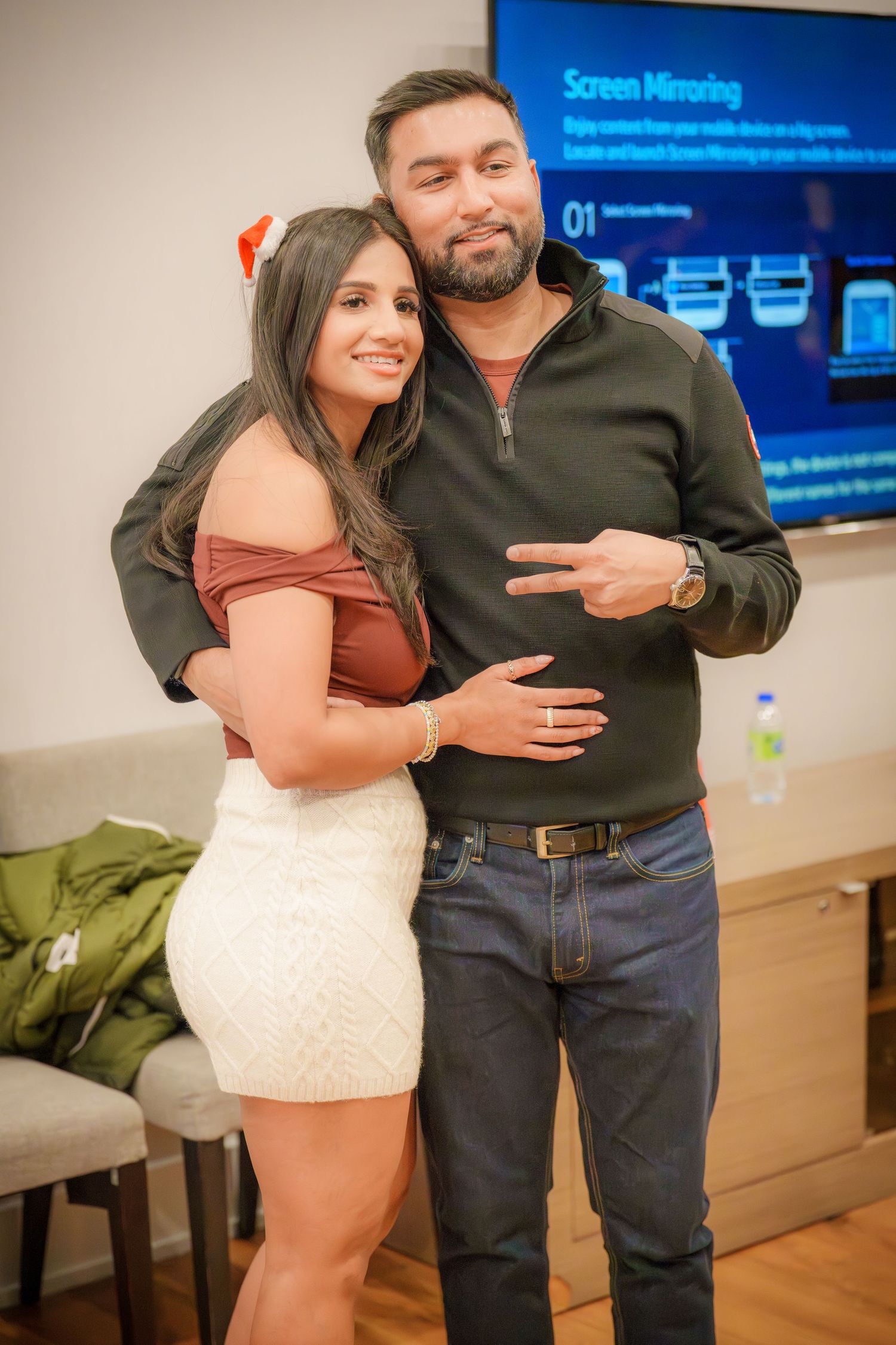 People celebrating at an indoor party with a blue screen display in the background.