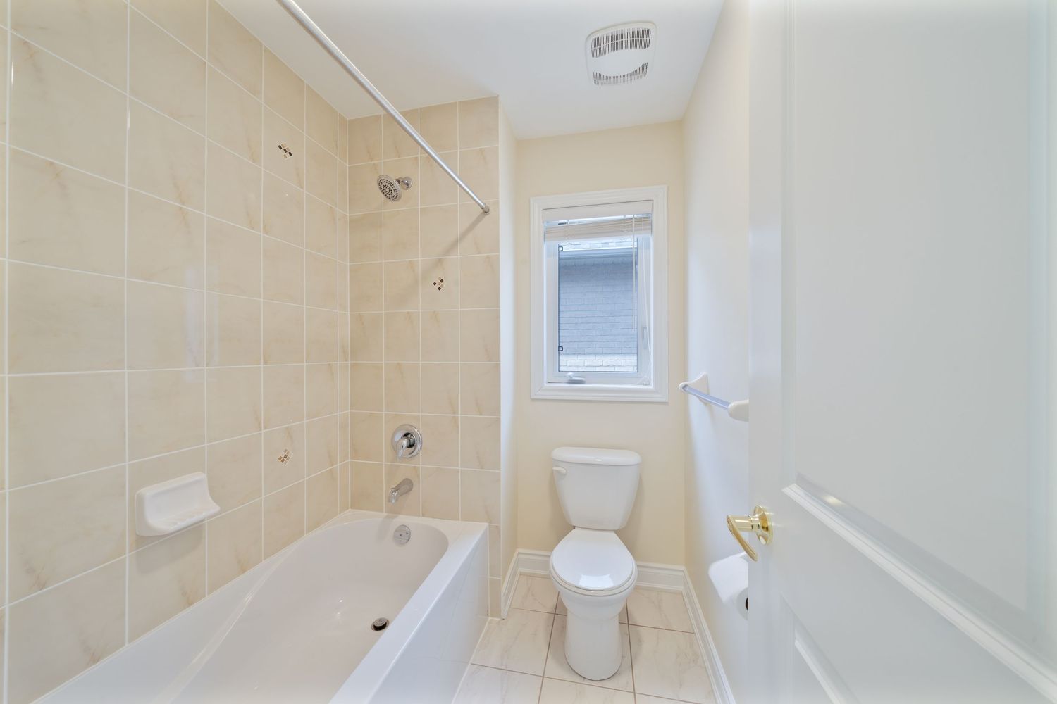 Modern bathroom interior with beige tile walls, white fixtures, and glass shower enclosure in a residential setting.