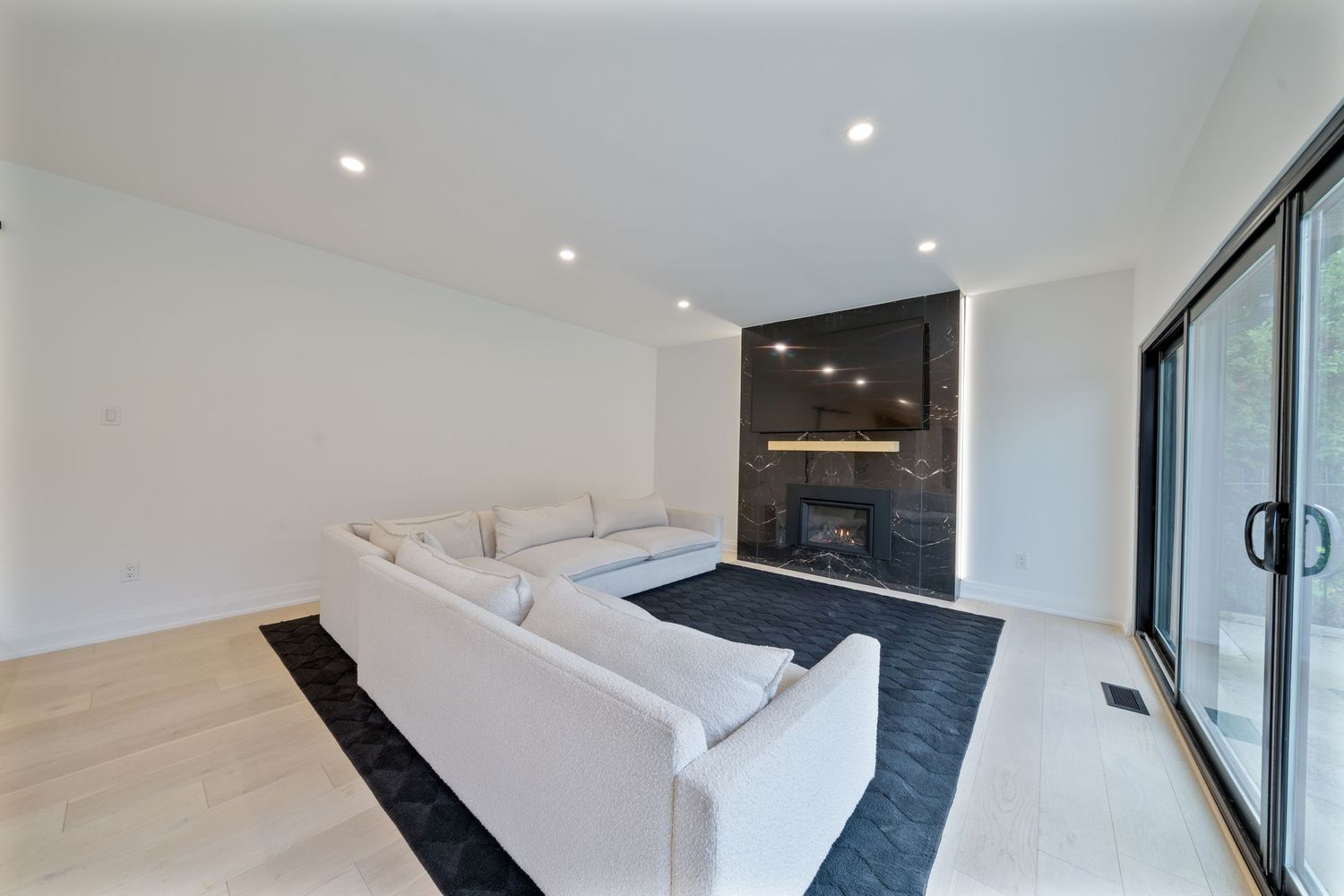 Modern minimalist living room with black accent chairs and floor-to-ceiling windows offering natural light.