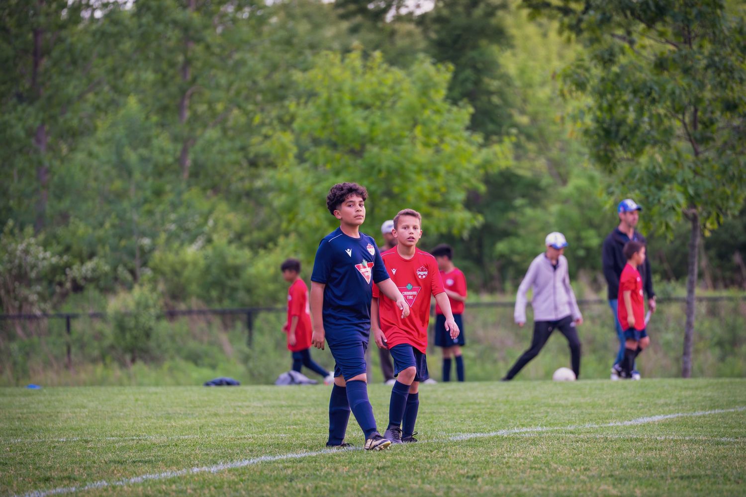 Youth soccer players practice drills and exercises on a grassy field during an outdoor training session.