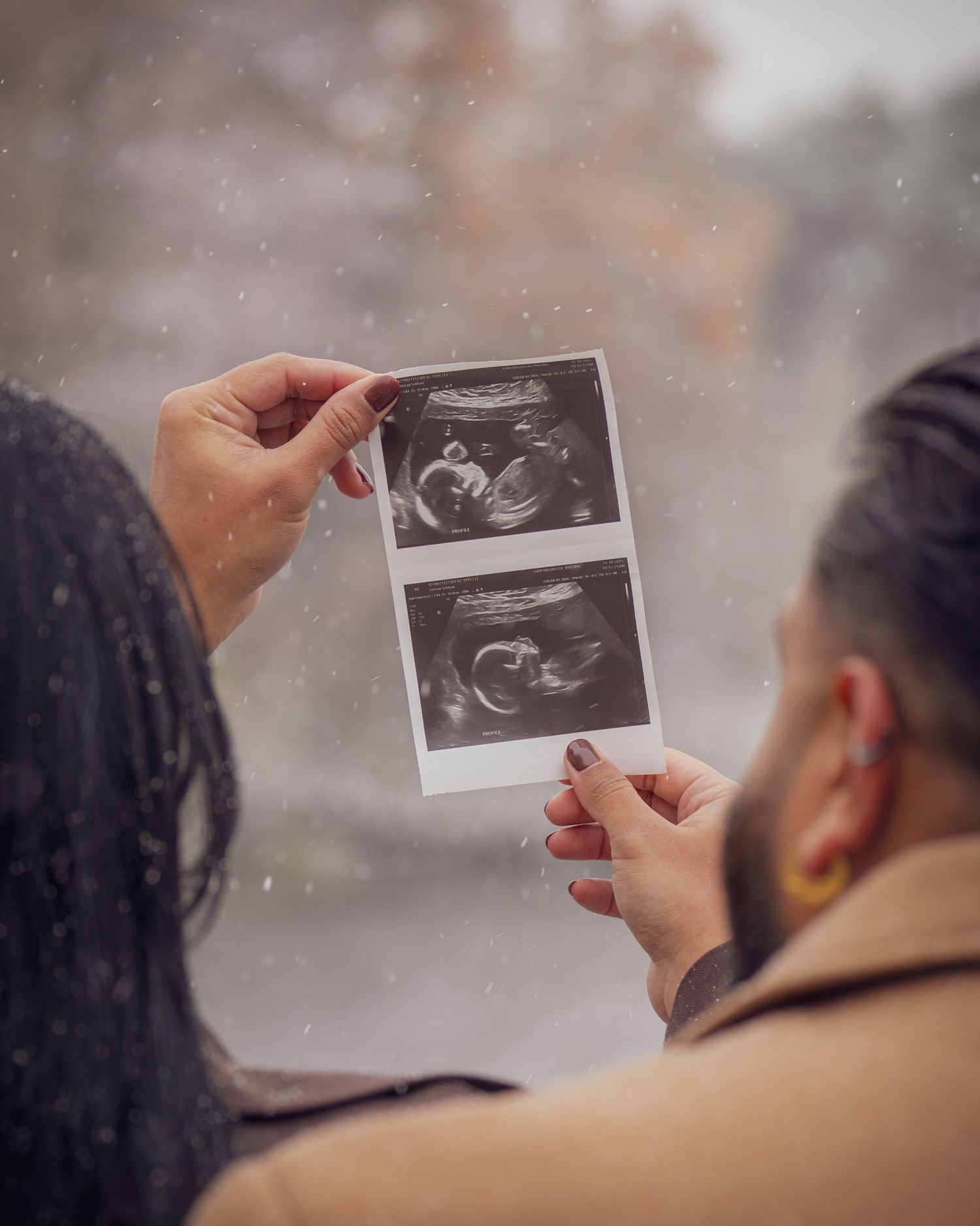 Couple examining ultrasound photos together during pregnancy announcement.