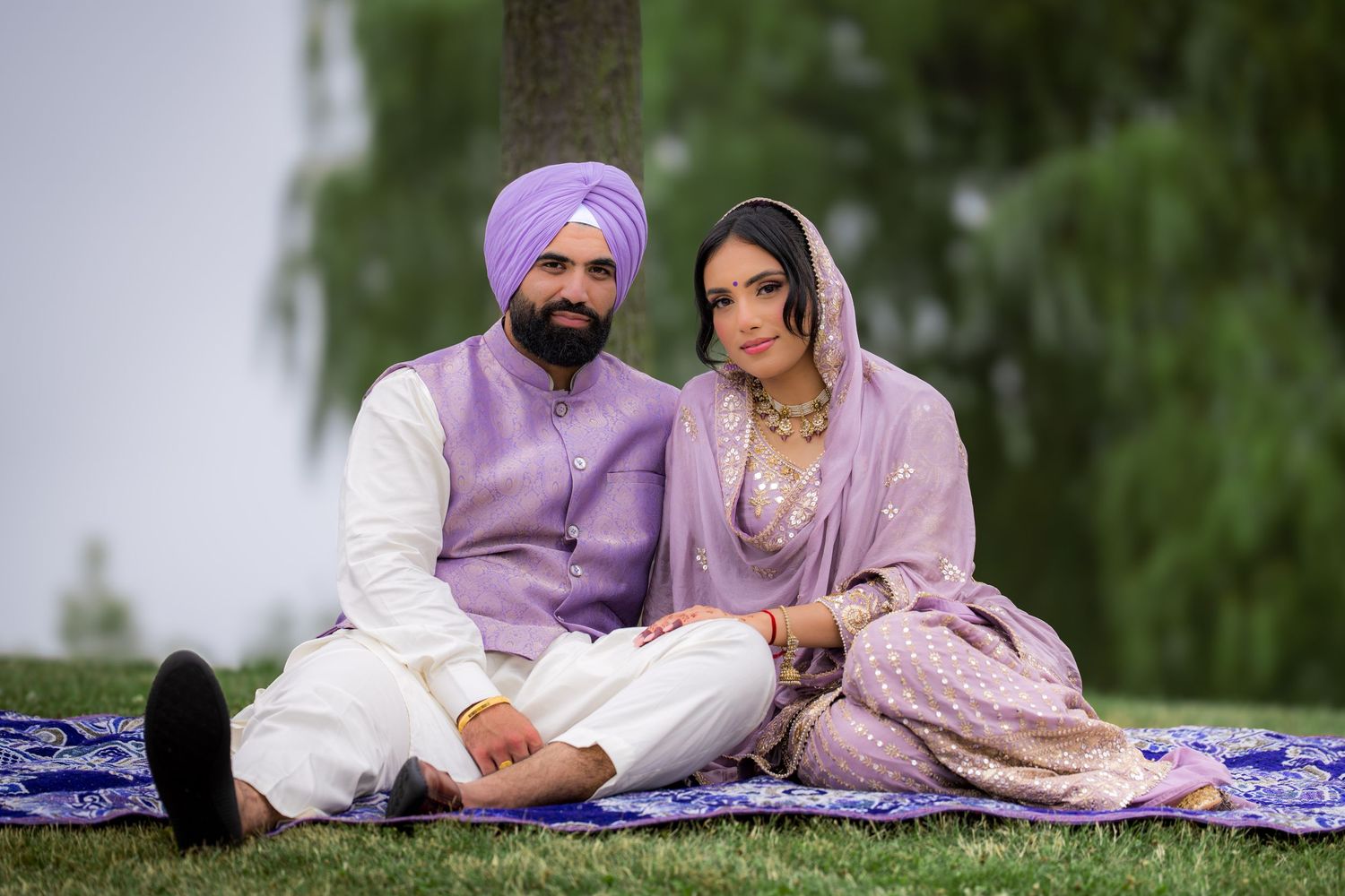 A romantic outdoor photoshoot featuring a couple in coordinated purple and white traditional clothing.