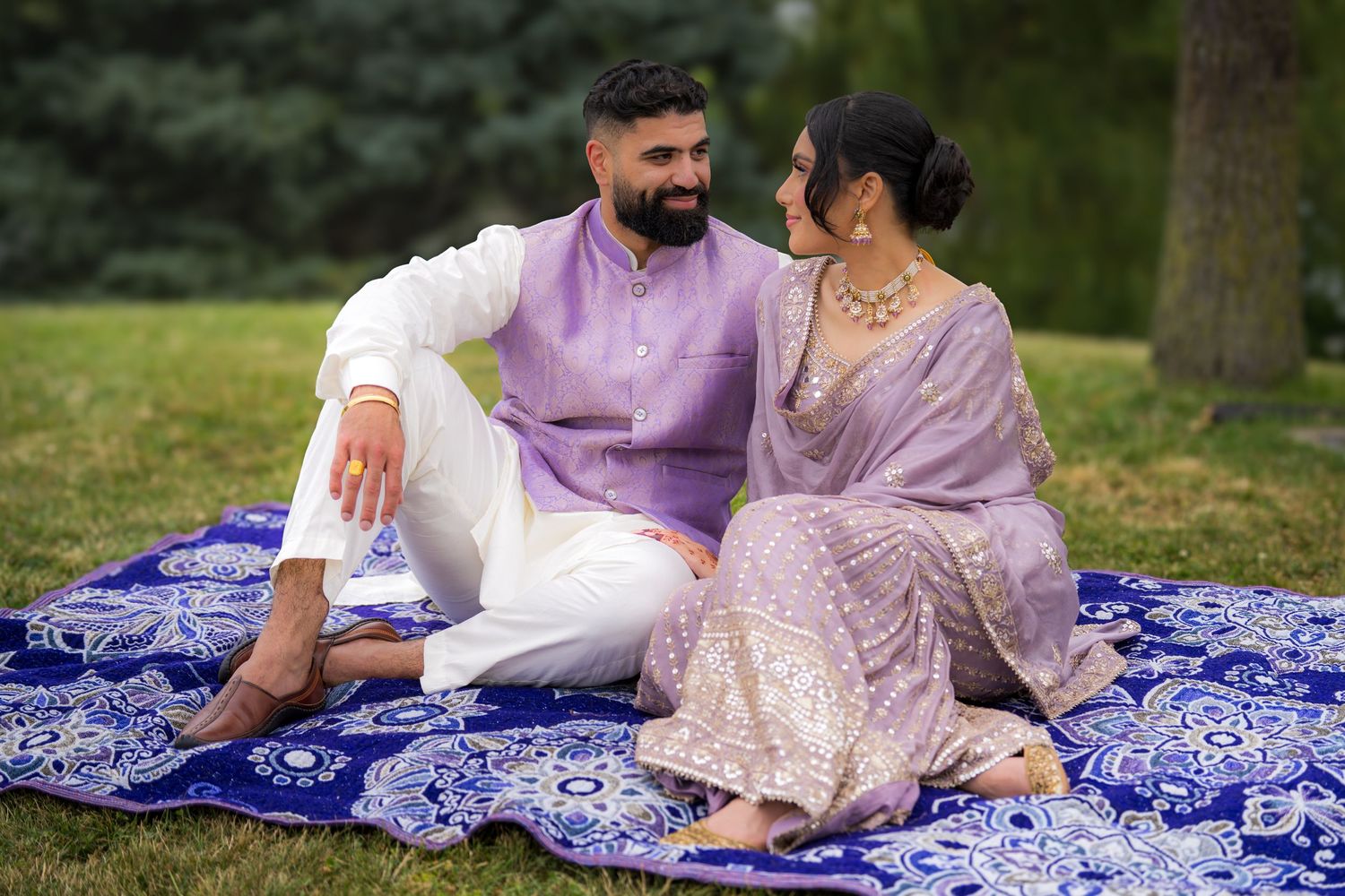 Intimate outdoor photo series of couple in coordinated traditional outfits on blue blanket.