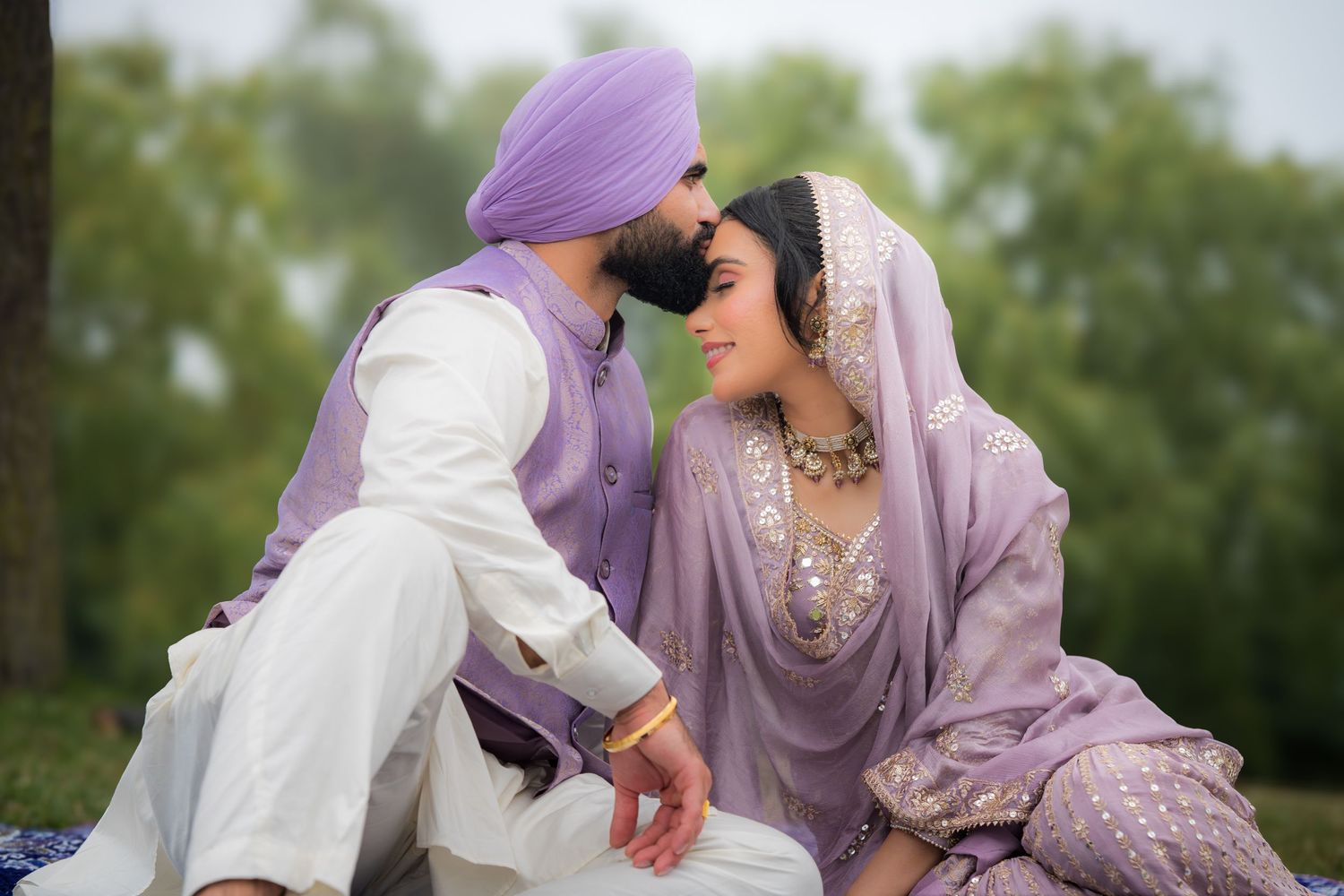 Outdoor wedding photography featuring couple in coordinated purple and white traditional dress.