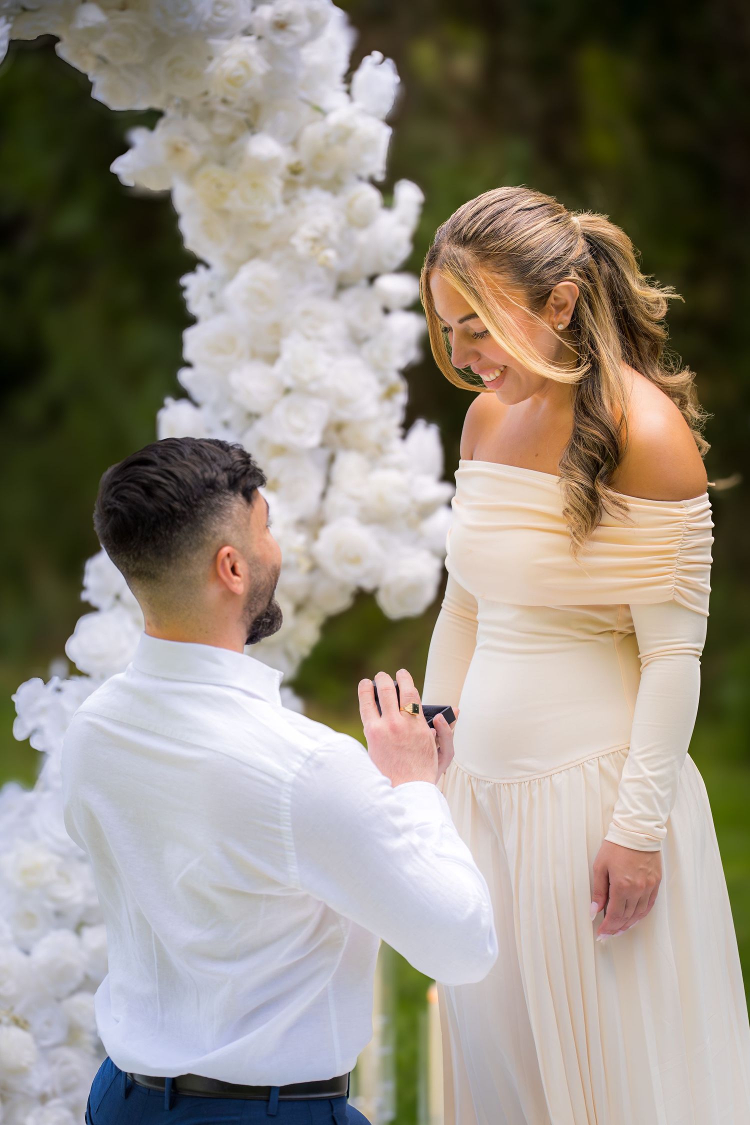 A proposal scene with white floral arrangements and candles creating a romantic atmosphere.