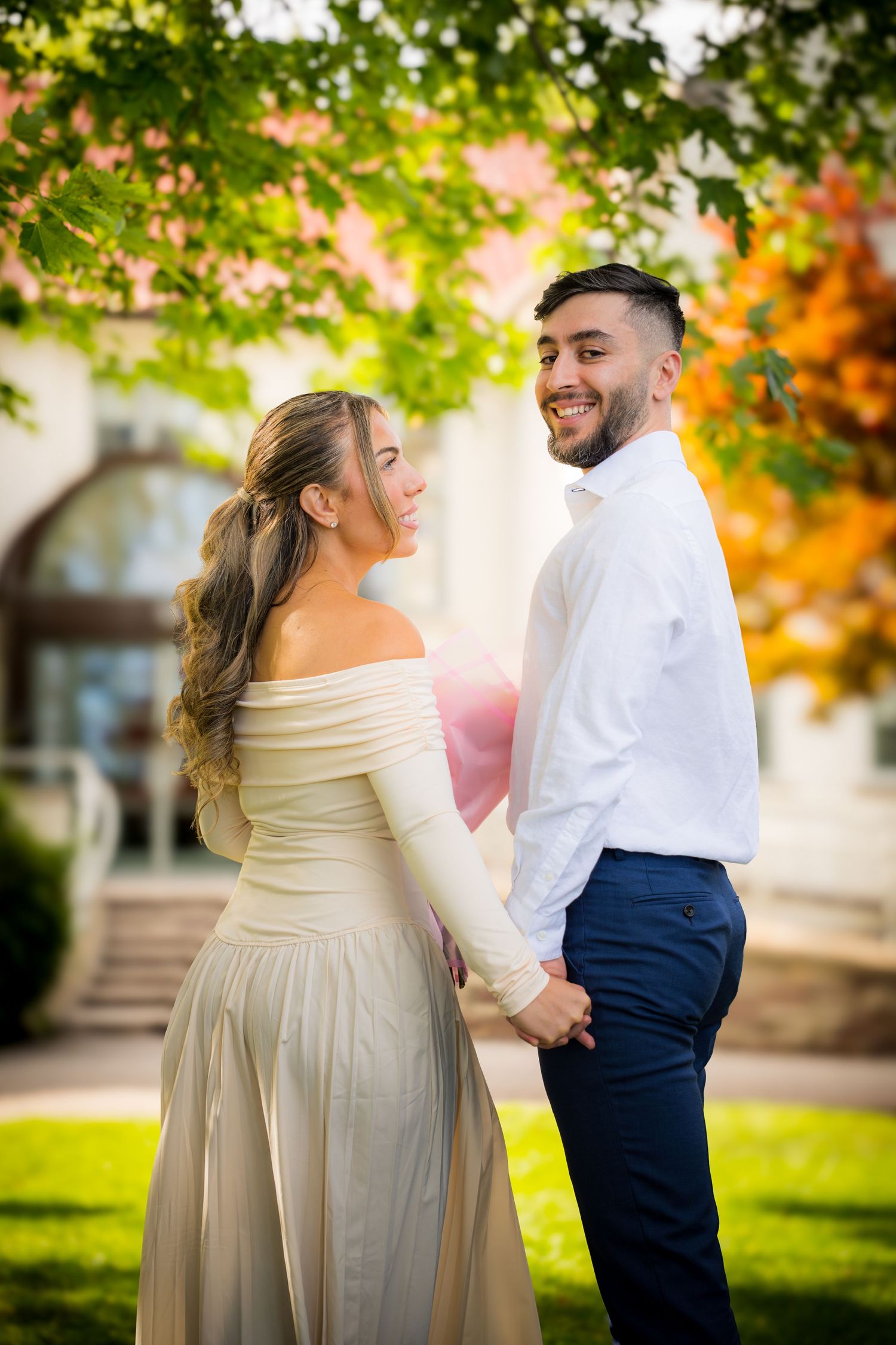 A couple shares intimate moments during their outdoor photo session under green trees.