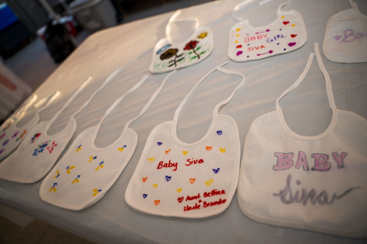 Baby bibs arranged with personalized decorations and messages.