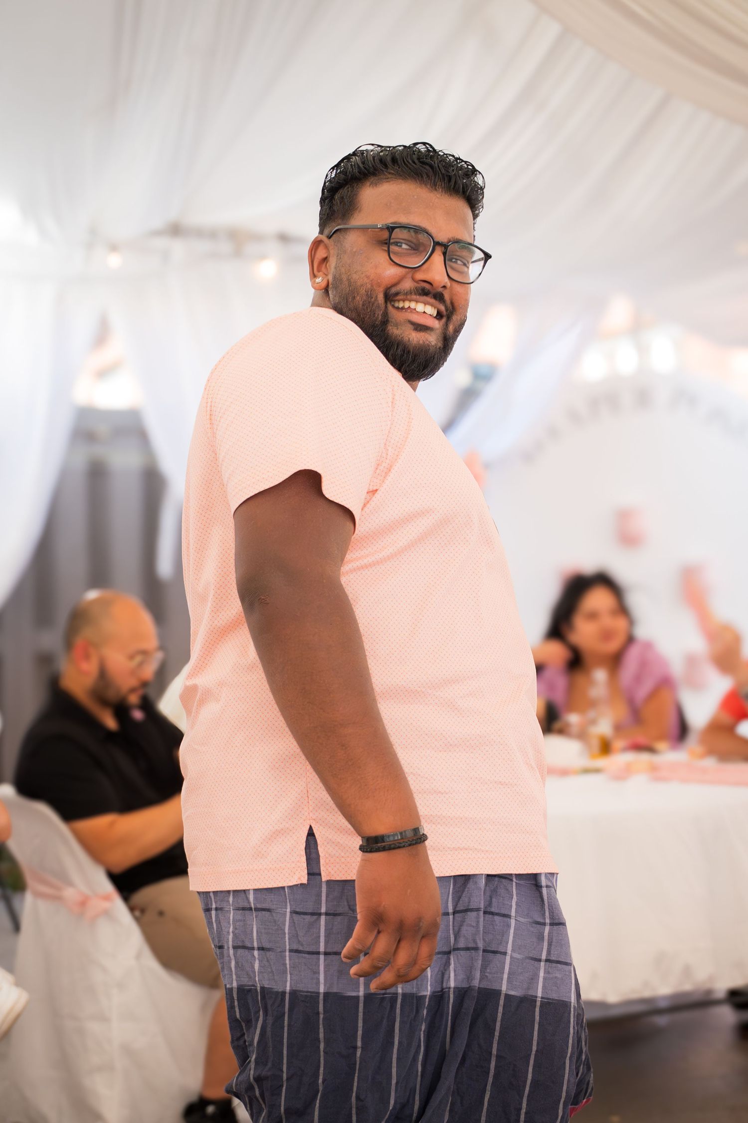 Guest in a salmon-colored shirt dancing and smiling at a social gathering.