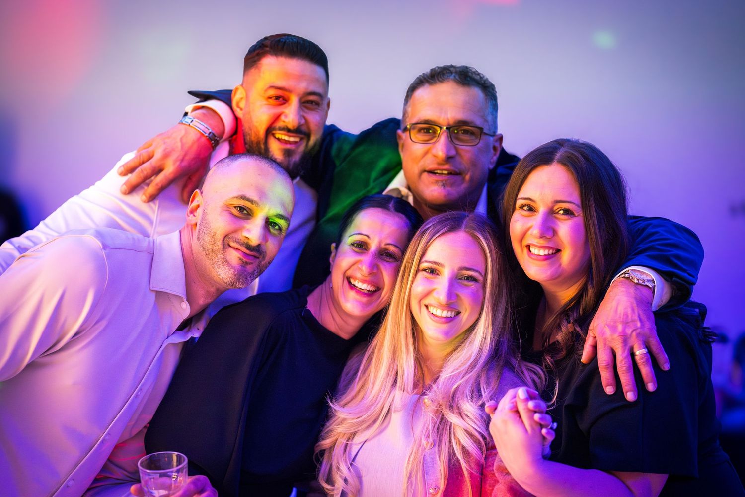Friends posing together for photos under purple and blue mood lighting at an event.