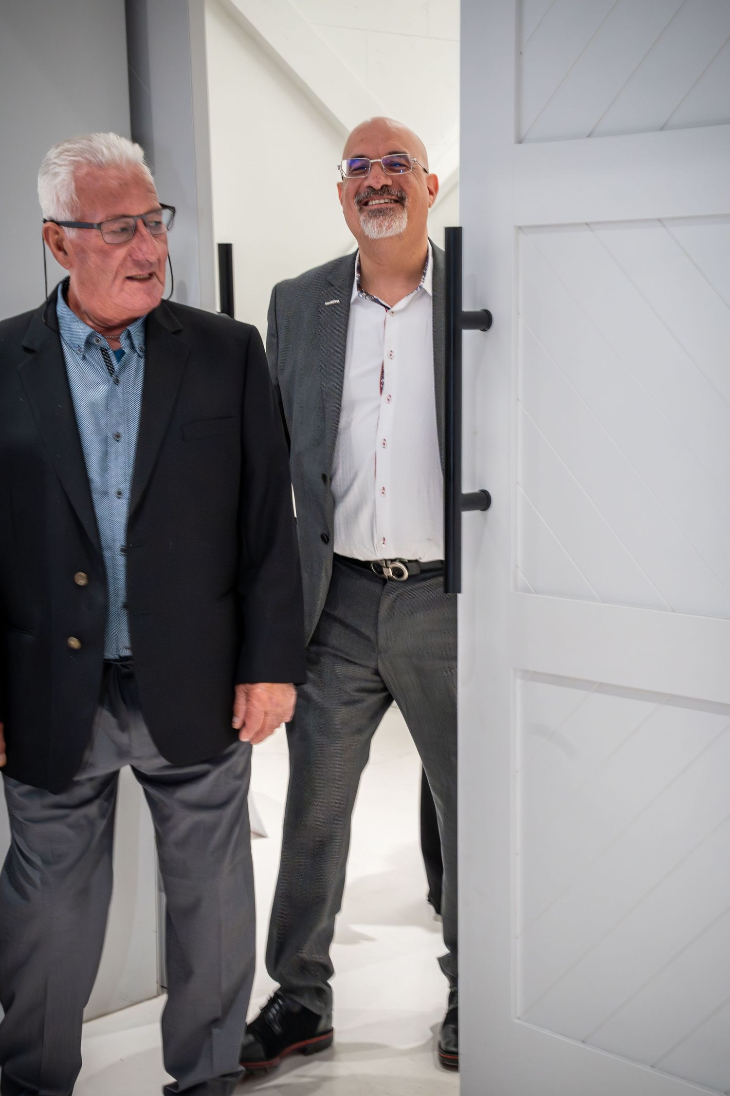 Professional gathering of colleagues in business attire by a white door.