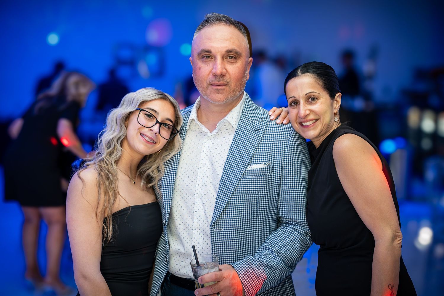 Party guests dancing and socializing at an event with blue lighting and festive atmosphere.