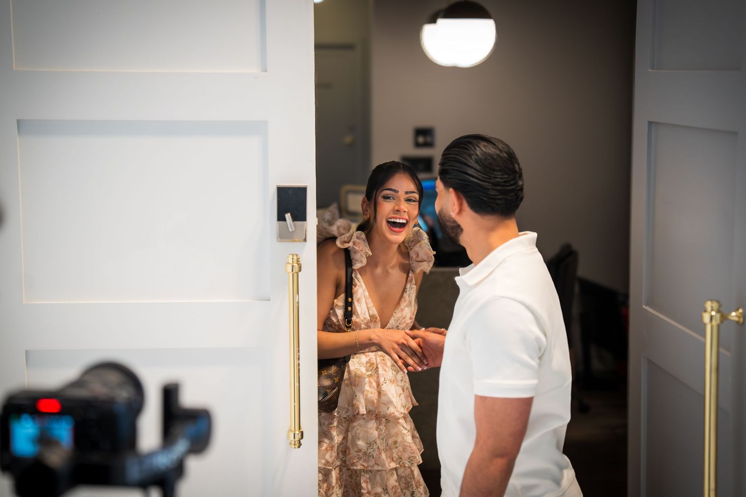 Bride and groom sharing a joyful moment in a doorway, with a camera in the foreground capturing their wedding day.