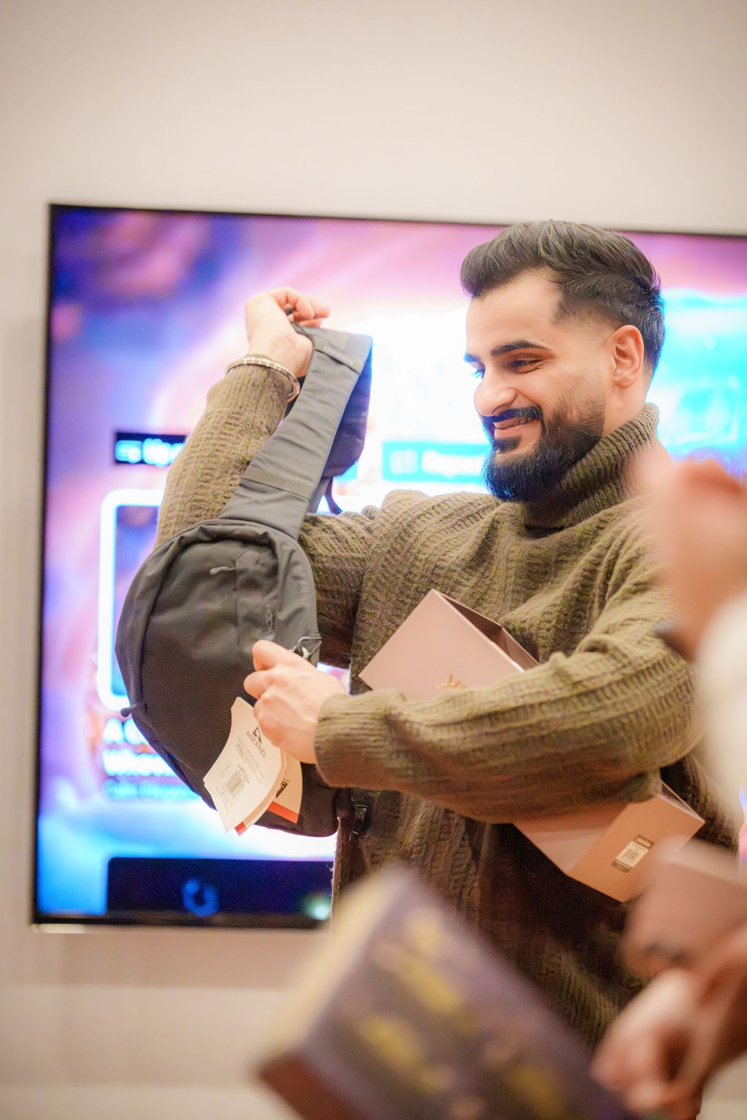 Person in a knit sweater laughing and enjoying themselves at a social gathering.
