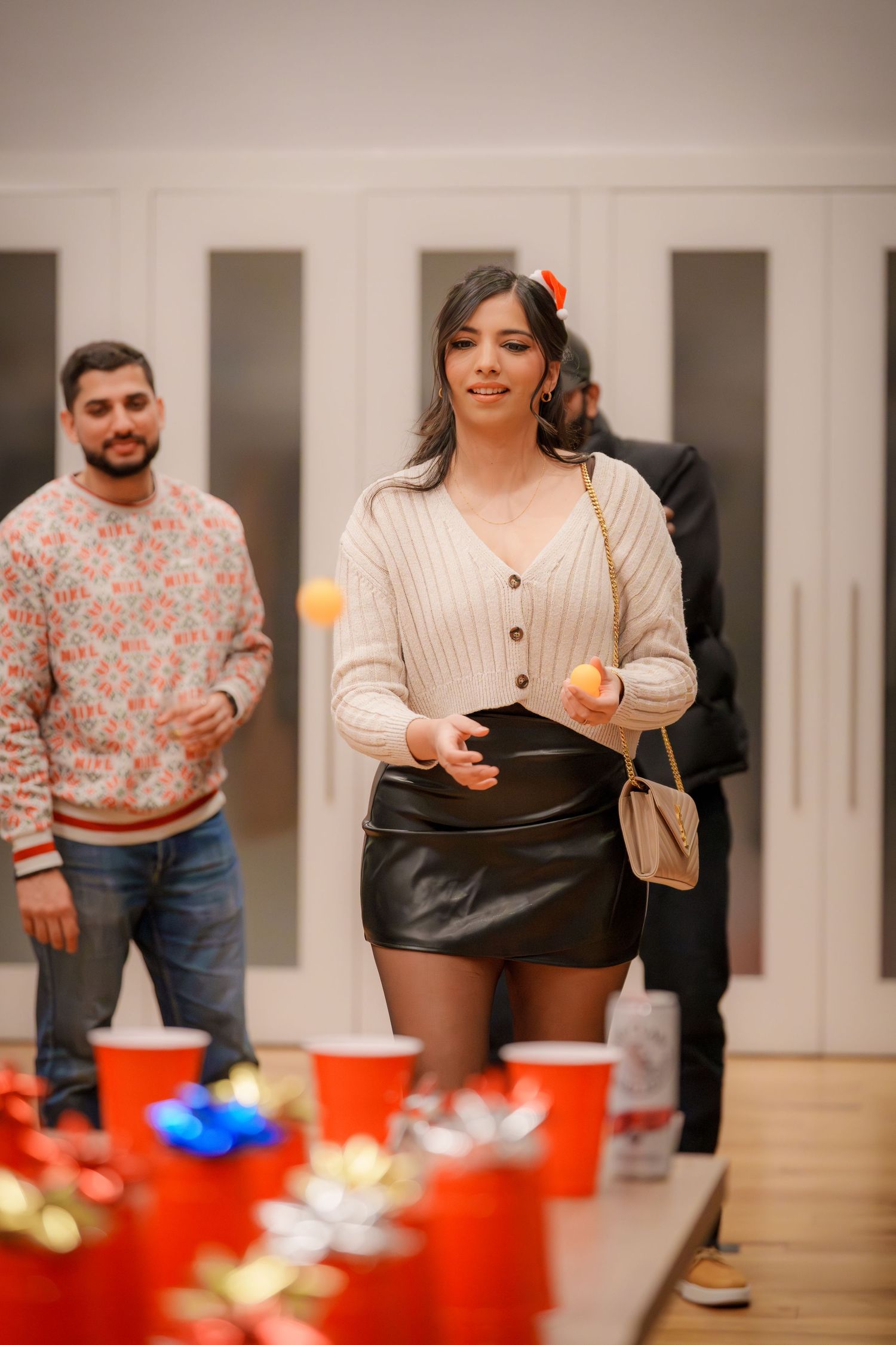 Group playing a party game with red cups on a table at an indoor gathering.