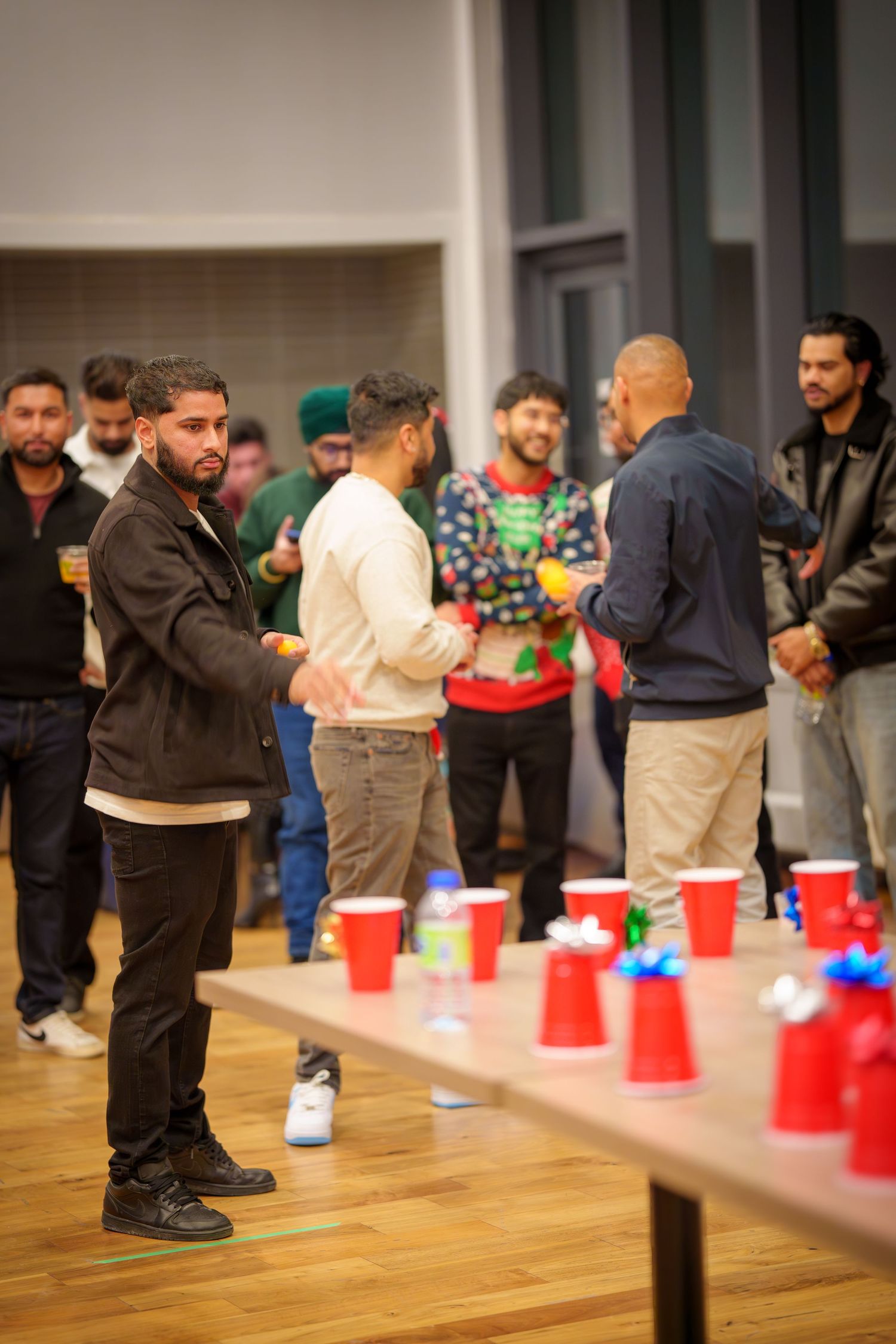 Participants leaning down to play a game with red plastic cups on a hardwood floor.