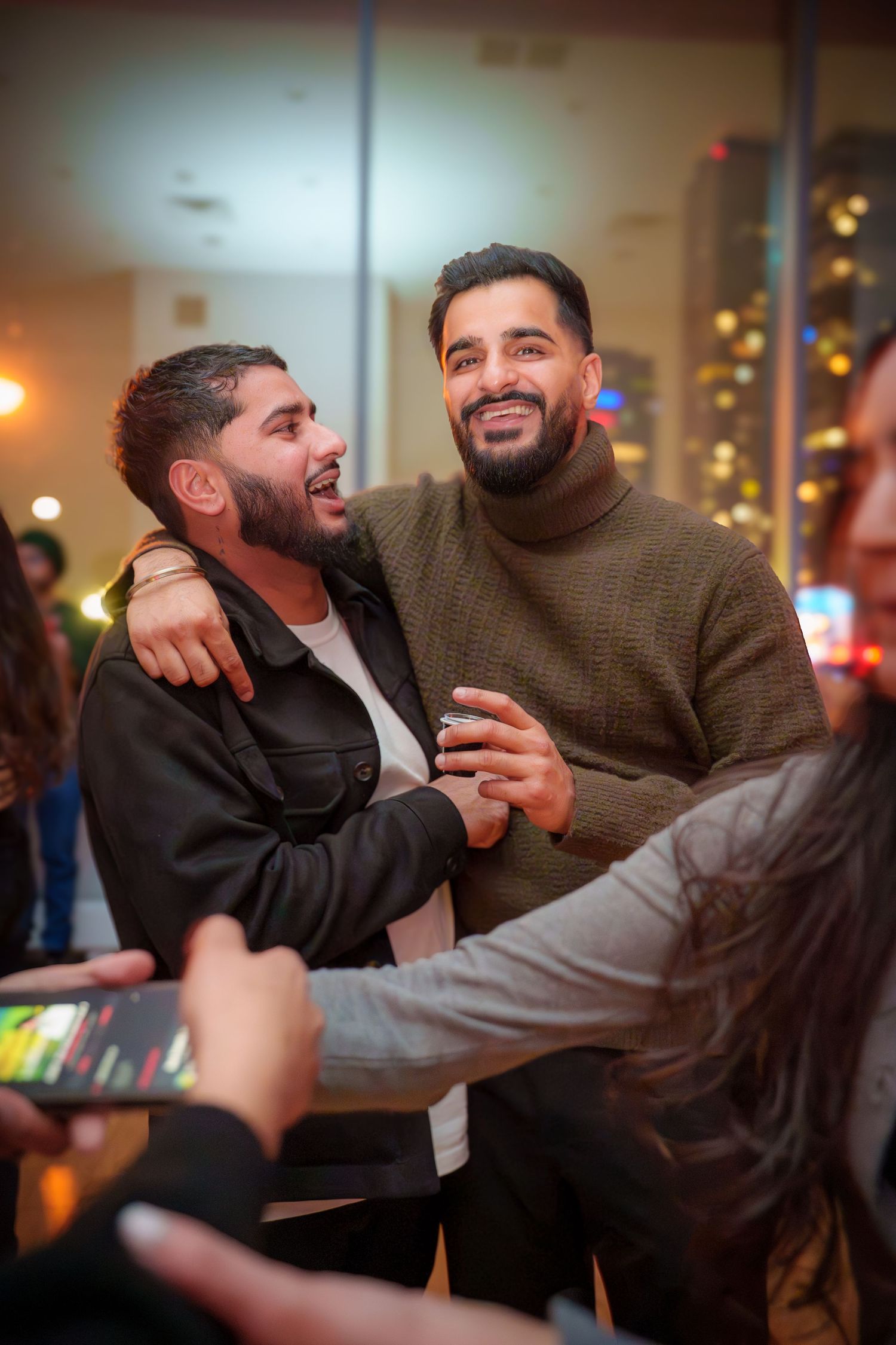 Friends playfully wrestling and laughing together at a social gathering.