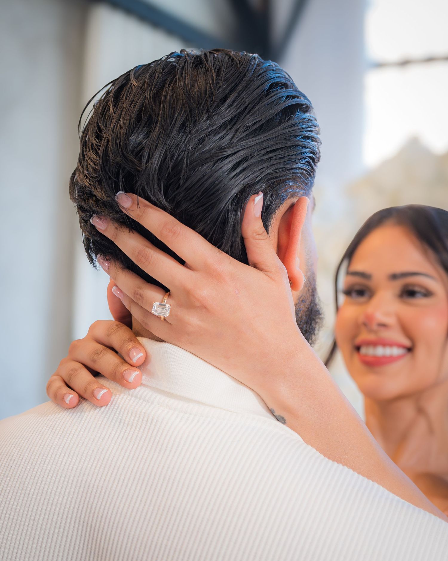 Bride-to-be showing off her diamond engagement ring while embracing her fiance.
