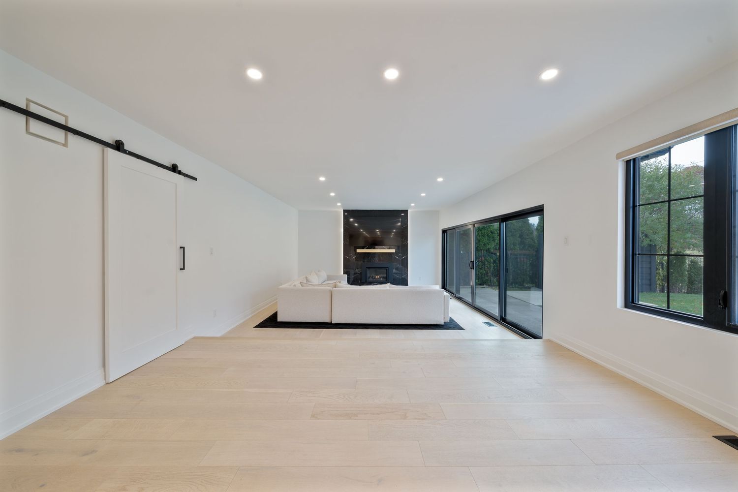 Modern open concept kitchen and living room with white walls, recessed lighting, and sleek minimalist design.