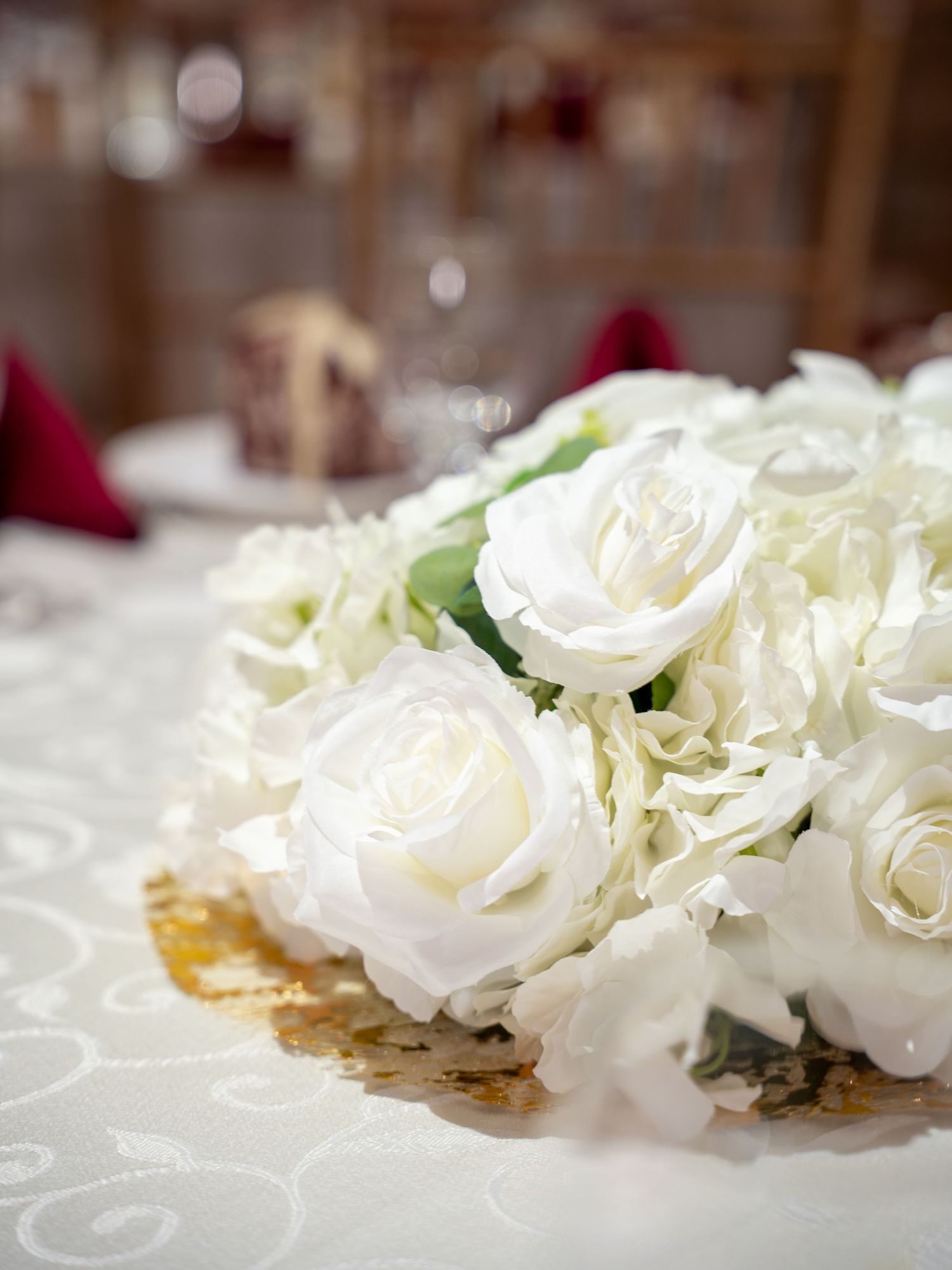 Close-up of white rose floral arrangements on elegant table settings with delicate lace details.