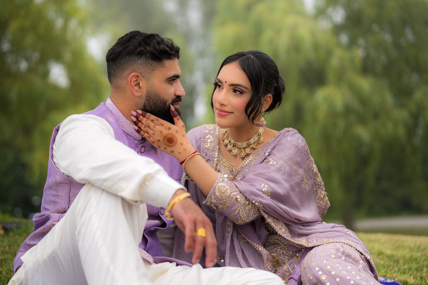 Couple in traditional South Asian formal wear shares intimate moment during outdoor photoshoot.