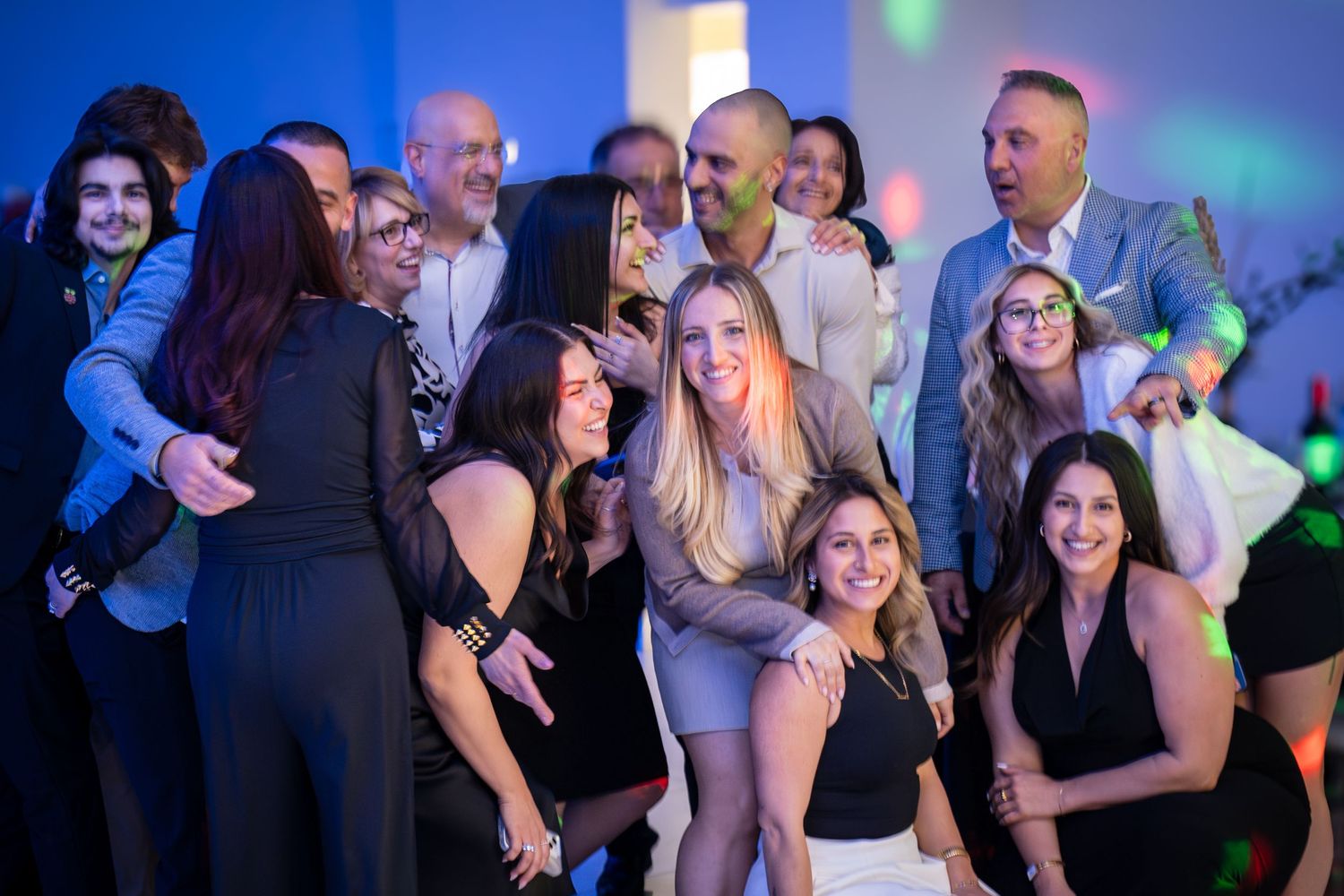 Energetic crowd enjoying themselves on a dance floor with atmospheric blue lighting.