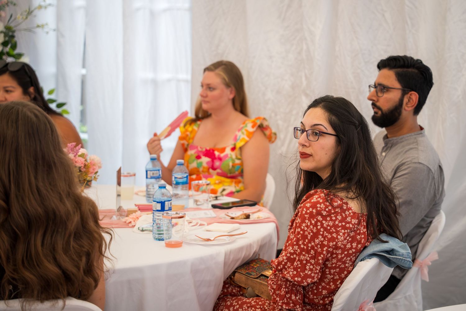 Guests enjoying food and conversation at elegant white-clothed tables.