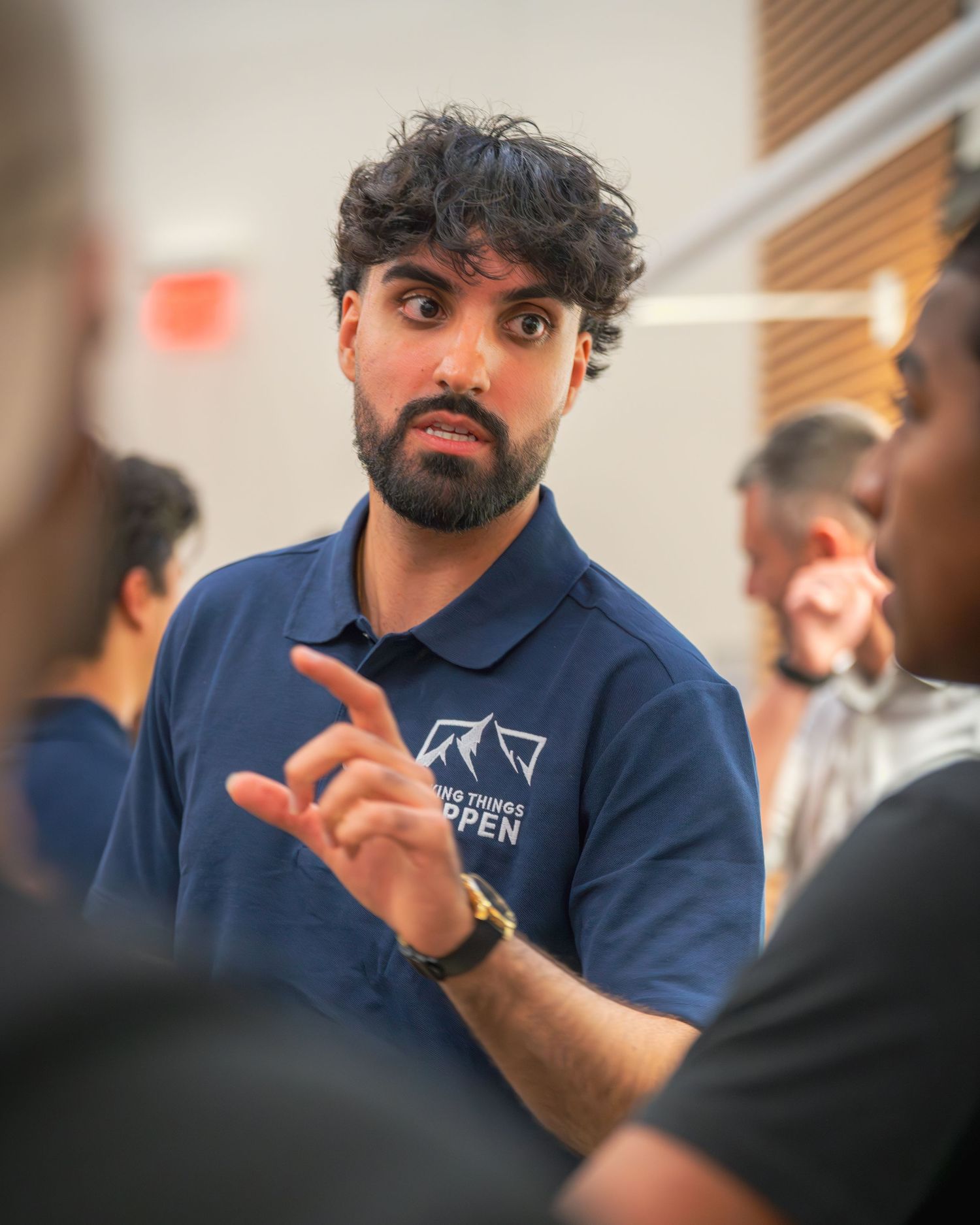 Speaker in navy branded polo shirt gesturing during discussion.